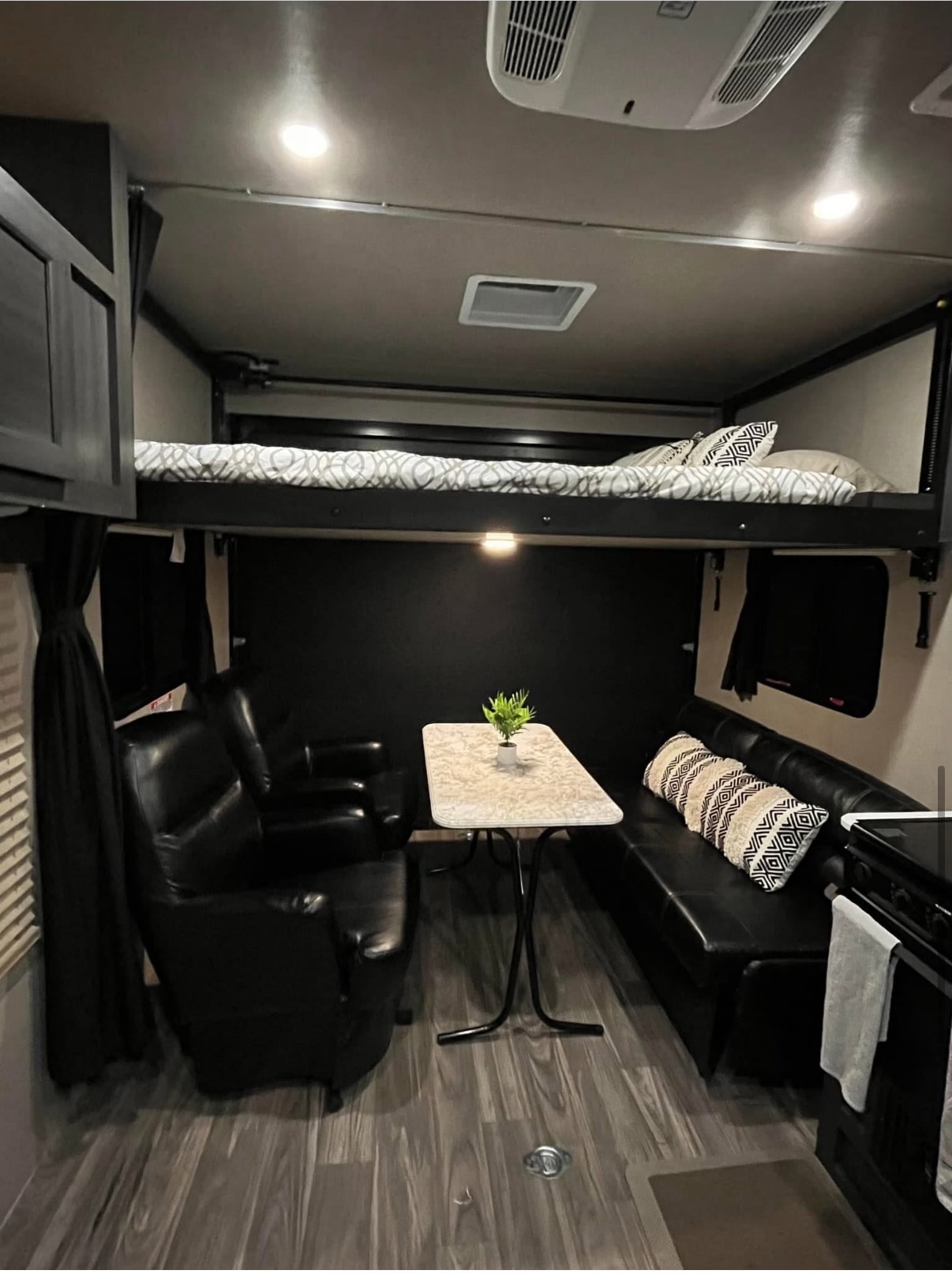 RV rental: A well-appointed interior with an elevated bunk, armchair, sofa, & table. Dark decor, wood floors.. Genesis Supreme Rv Genesis Supreme 2021