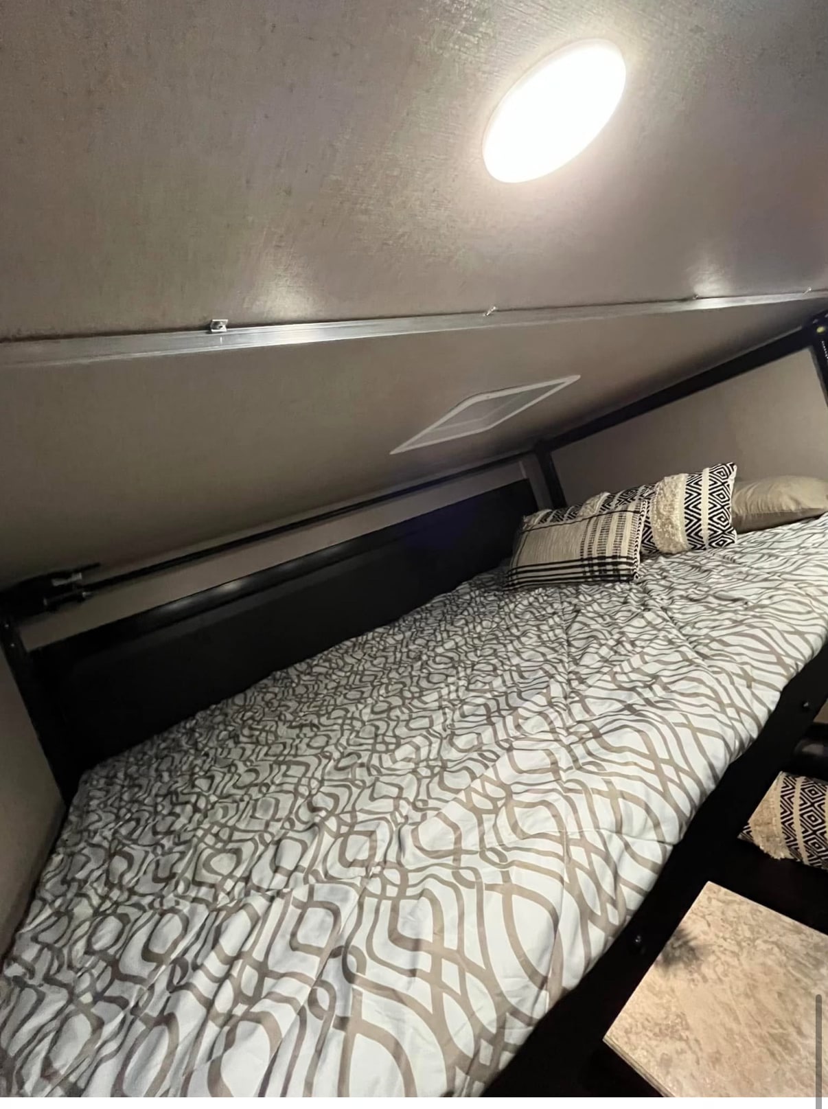 An RV rental's comfortable bedroom features a neatly made bed with graphic patterned bedding and overhead lighting.. Genesis Supreme Rv Genesis Supreme 2021