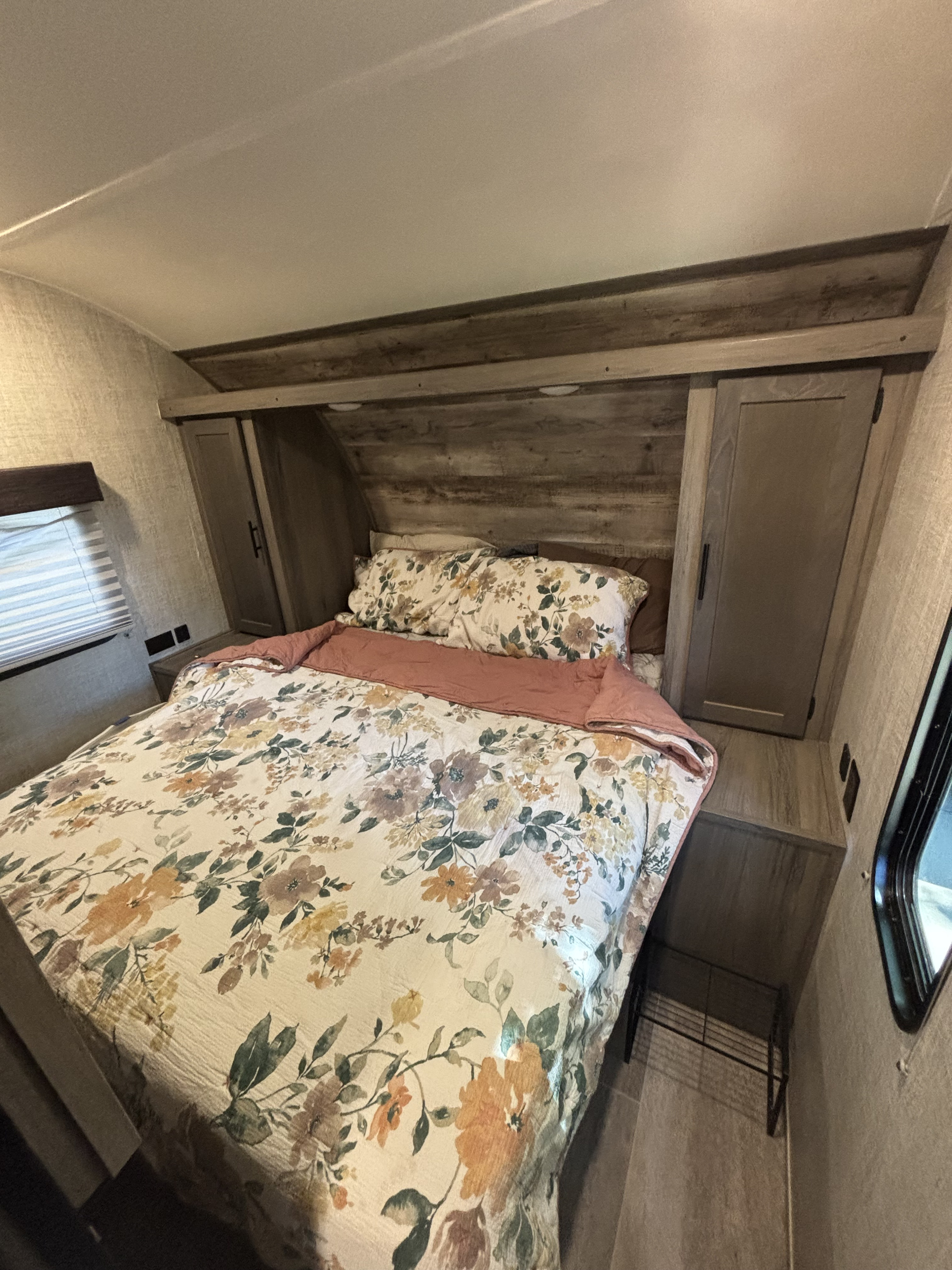 Cozy RV rental bedroom featuring floral bedding, built-in storage, and warm wood accents for a comfortable stay.. Gulf Stream Ameri-Lite 2021