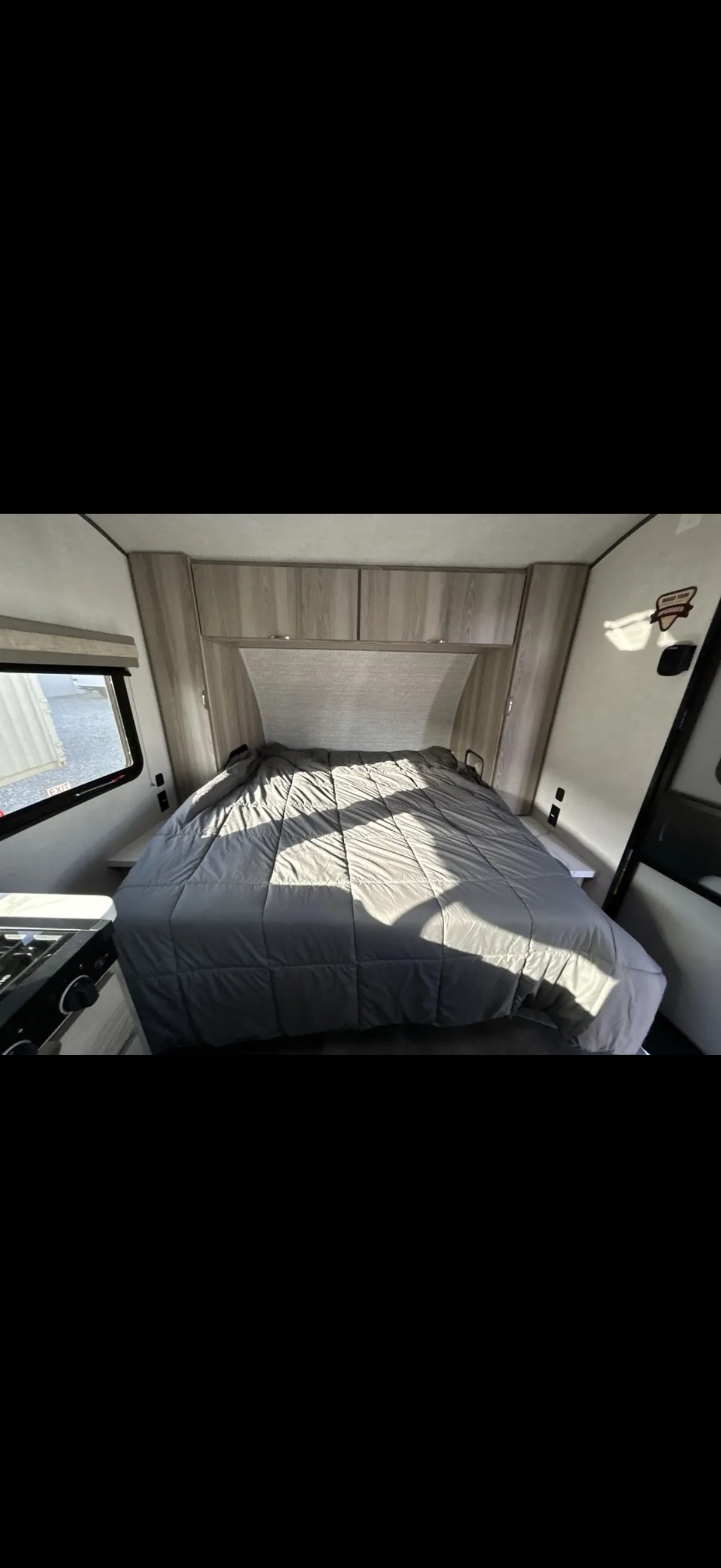 RV rental: Bright, modern camper interior with a spacious bed, overhead cabinets, and a compact kitchen.. Forest River Salem 2025