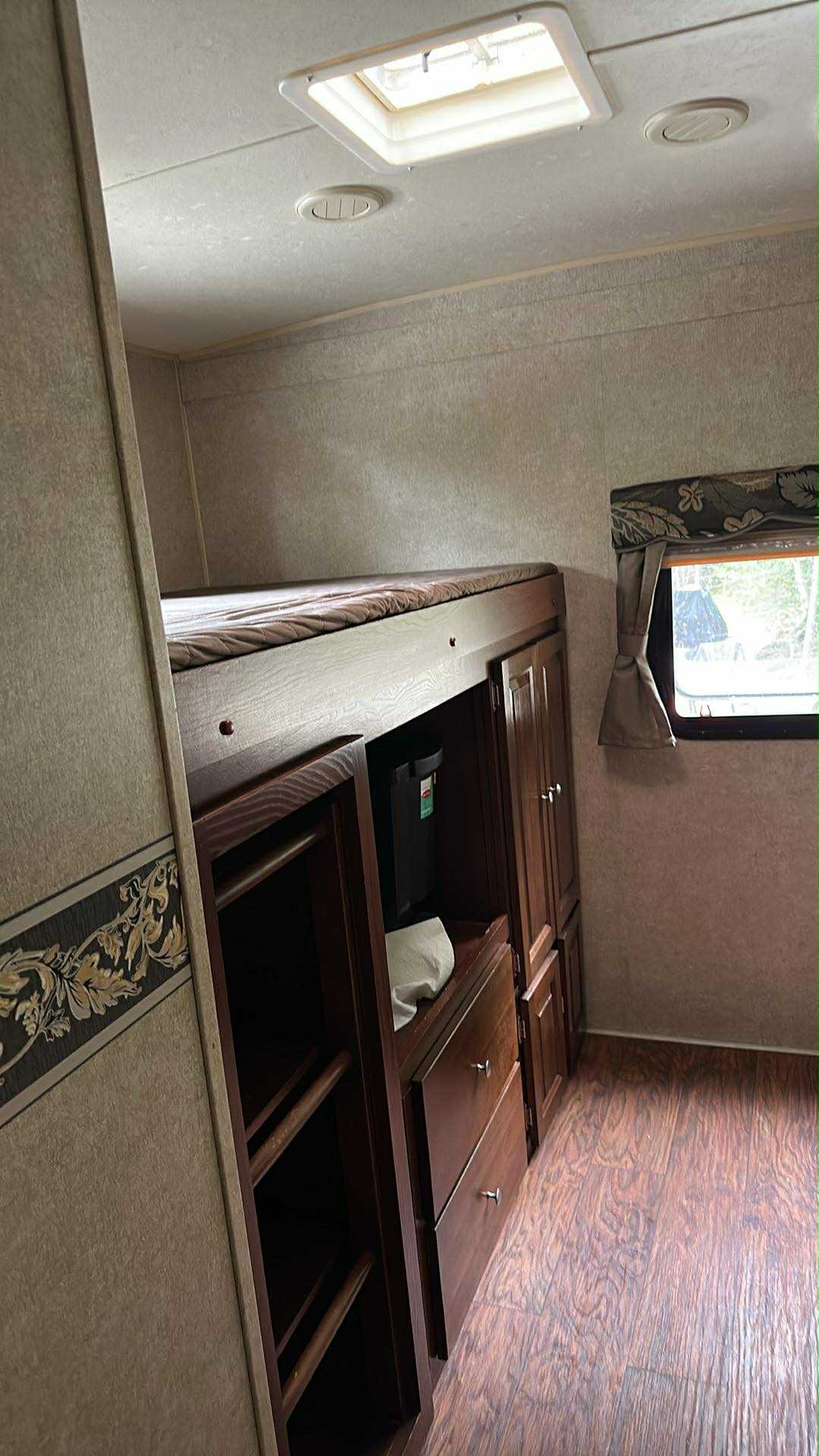 RV rental interior featuring a bunk bed over built-in storage (cabinets, drawers), window, and roof vent.. Forest River Rockwood Signature Ultra Lite 2015