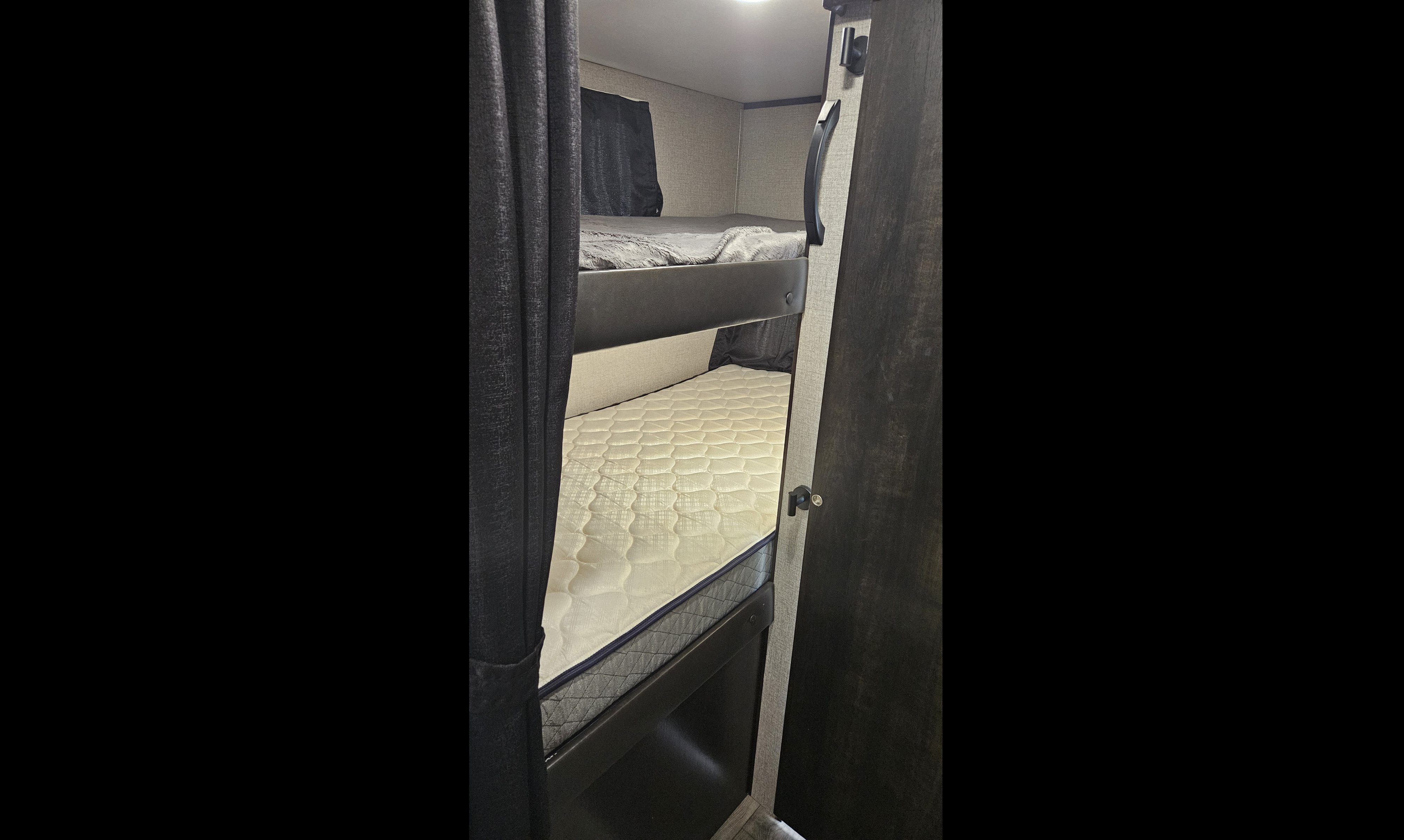 RV rental: Compact interior showing two cozy bunk beds. The top bunk has a grey blanket, the lower a white mattress.. Jayco Jay Feather 2020