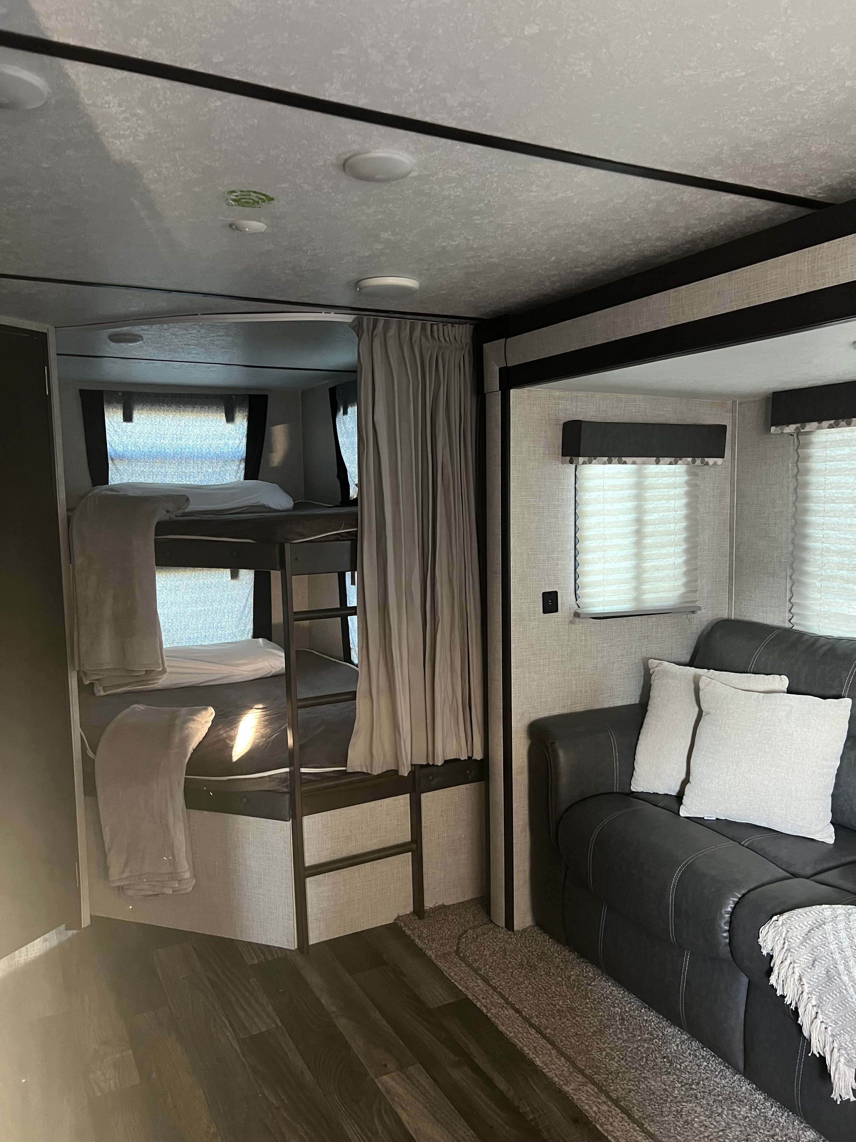 Explore this cozy RV rental interior featuring a practical bunk bed setup & comfortable sofa for your next adventure.. Keystone RV Bullet Ultra Lite 2020