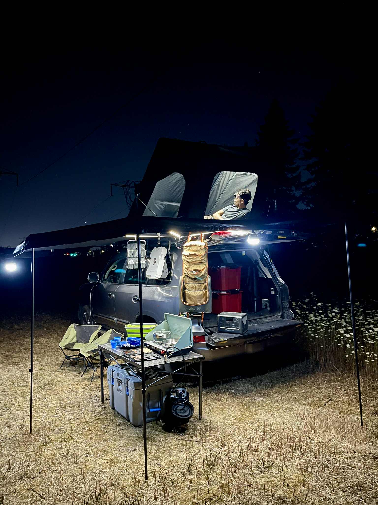 Night car camping setup: An SUV with a rooftop tent and awning provides an RV rental-like experience. Illuminated outdoor kitchen & relaxing space.. Lexus LX570 2014