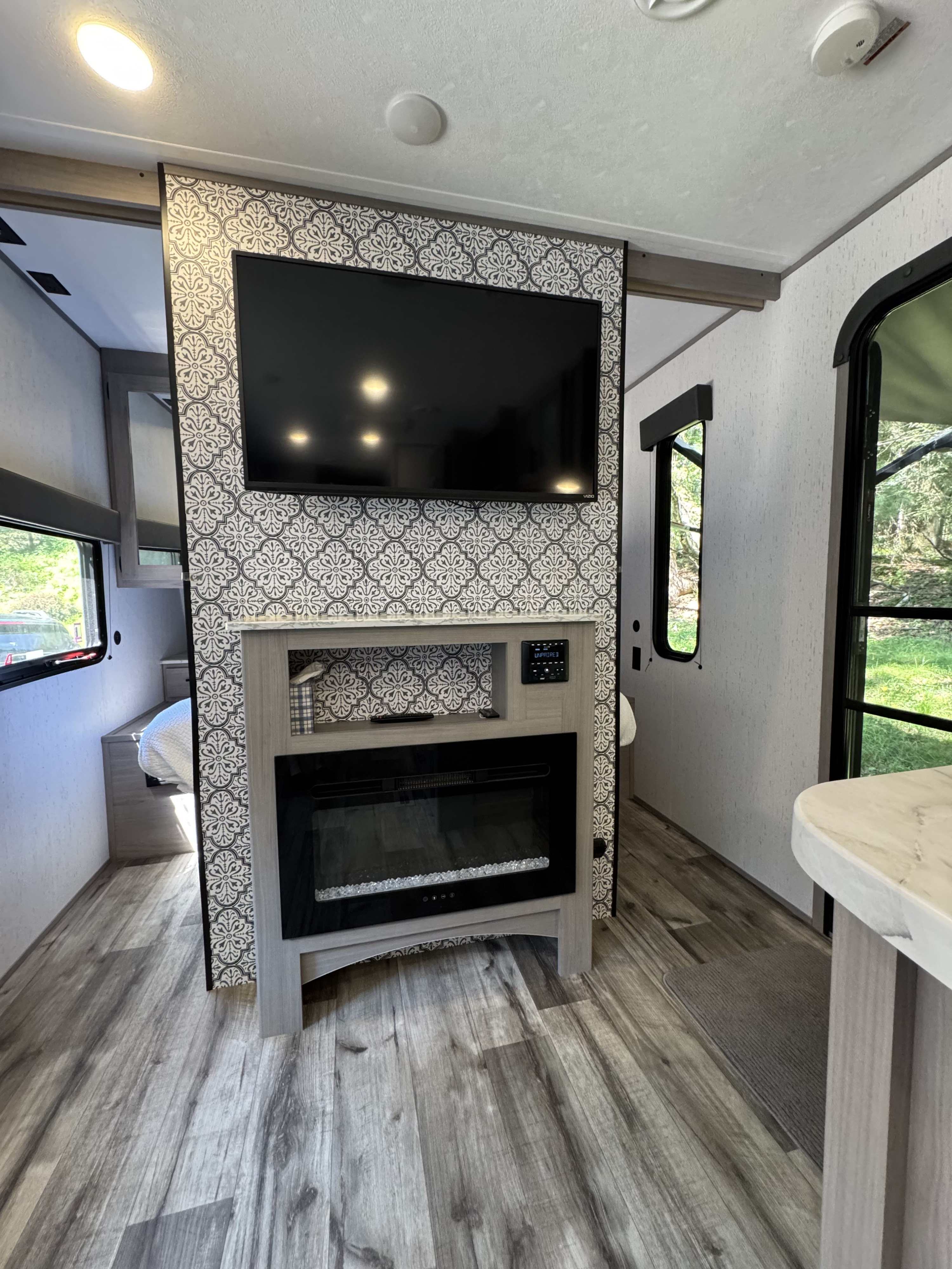 RV rental living space featuring a wall-mounted TV, electric fireplace, patterned decor, and vinyl plank flooring.. Dutchmen Coleman Lantern 2022