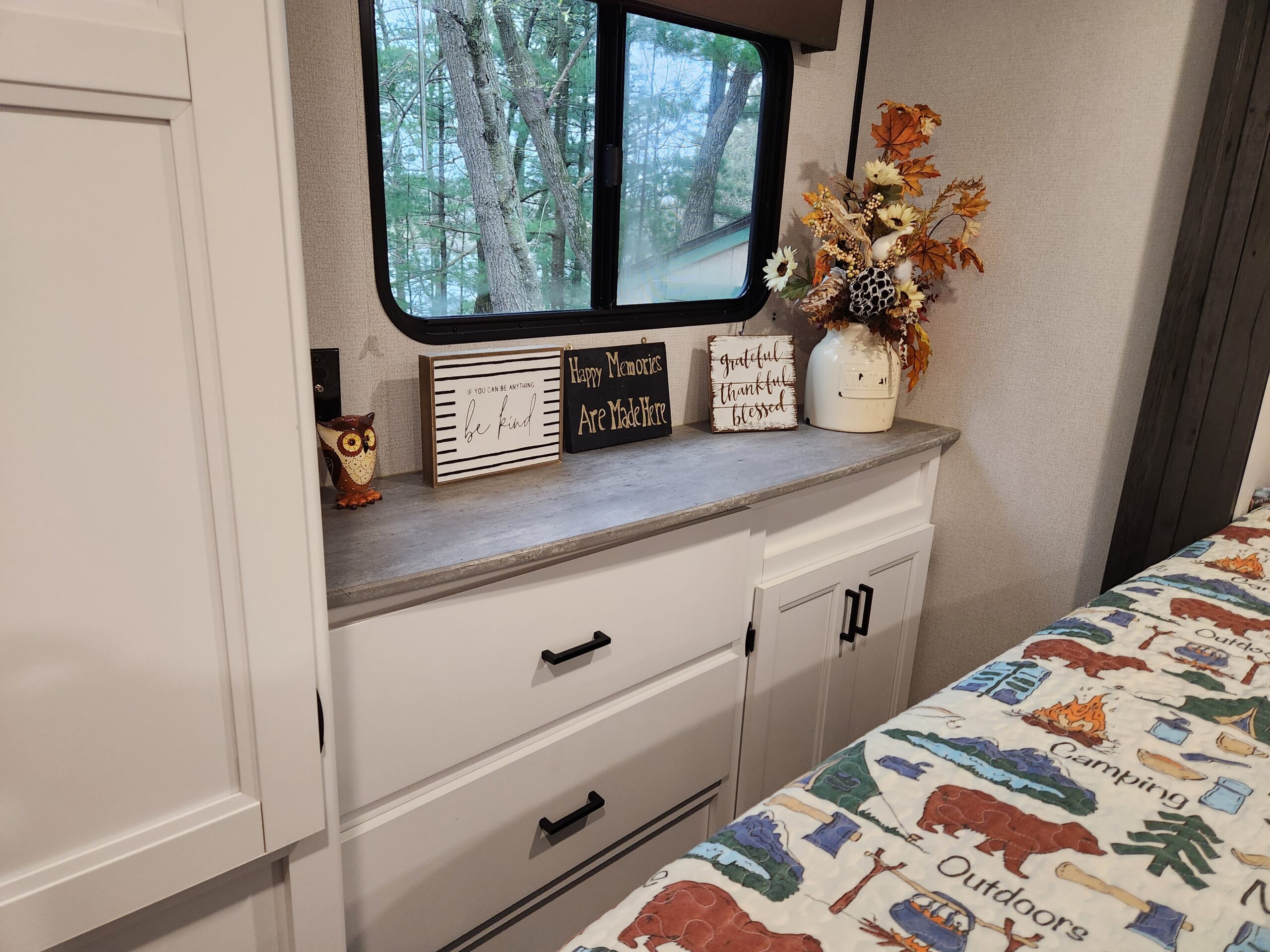 Charming RV rental bedroom with forest view, inspirational signs, and a fun camping-themed quilt.. Keystone RV Hideout 2022