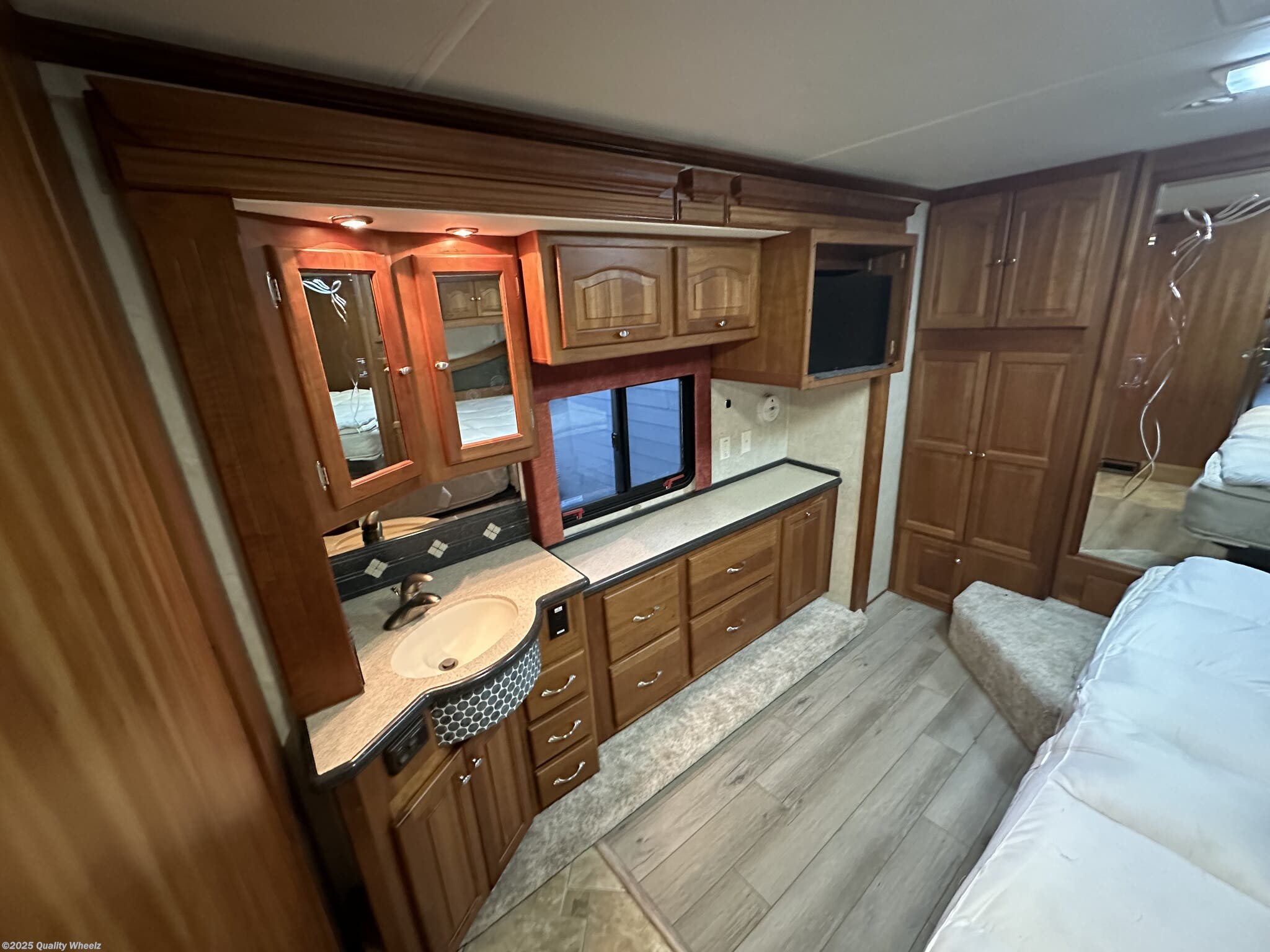 Explore this inviting RV rental interior: bedroom with vanity, sink, abundant wood cabinetry, and a TV for ultimate comfort.. Allegro Allegro Bus 2005