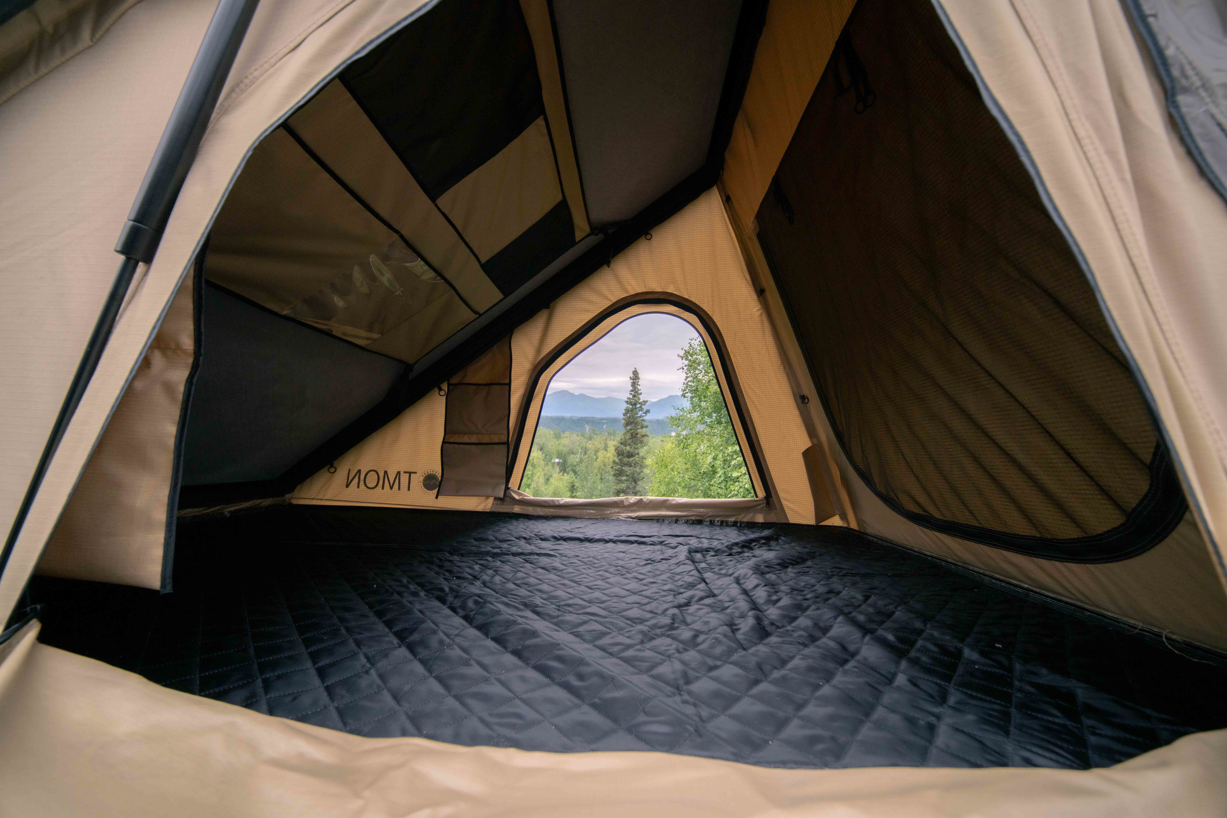 Interior of an RV rental rooftop tent: a comfy mattress with a scenic mountain and forest view, ideal for camping adventures.. Toyota FJ Cruiser 2007