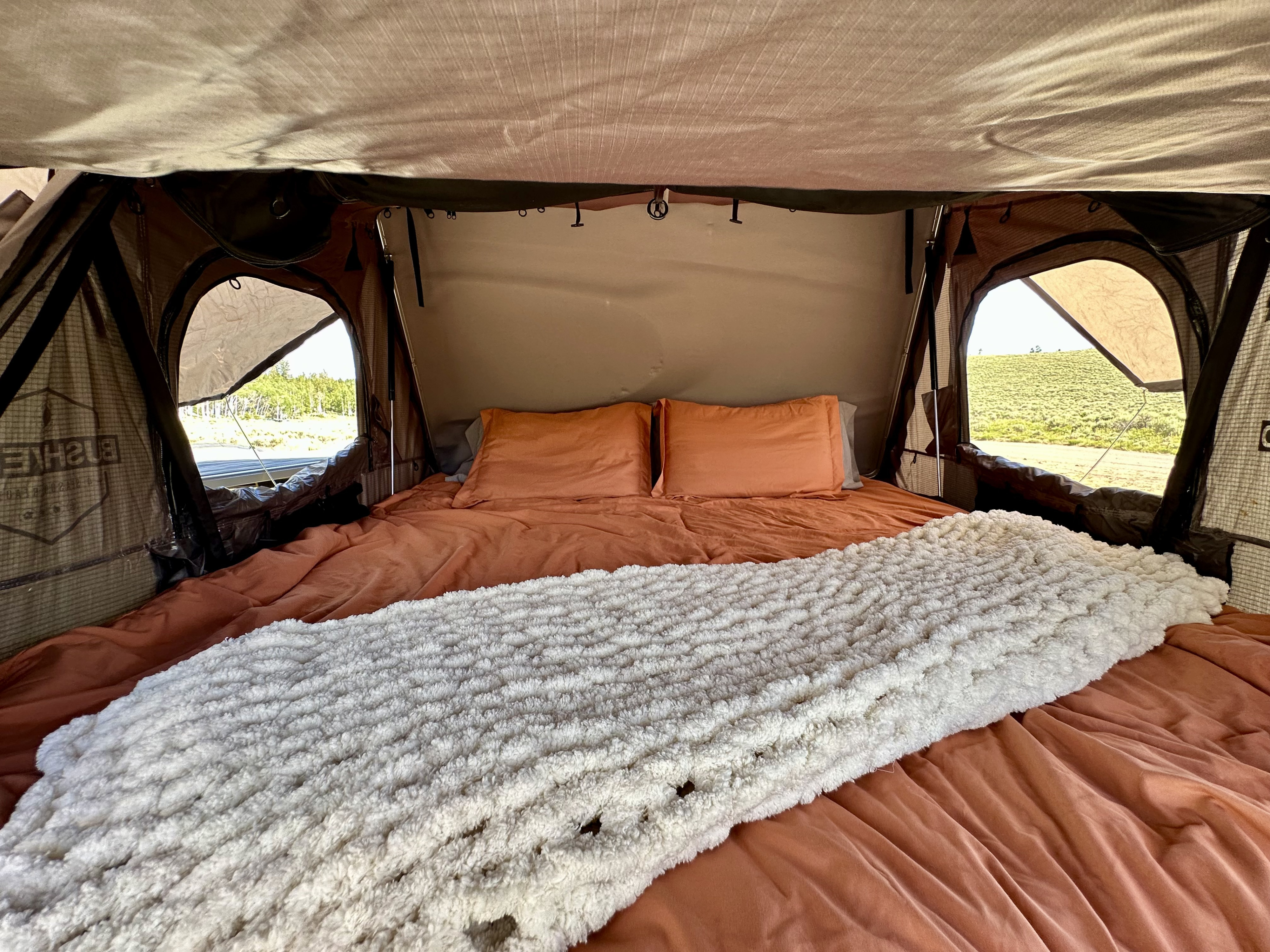 Cozy rooftop tent bed inside an RV rental, ready for adventure. Enjoy comfy camping with stunning views!. Addax Overland GE Summit 2023