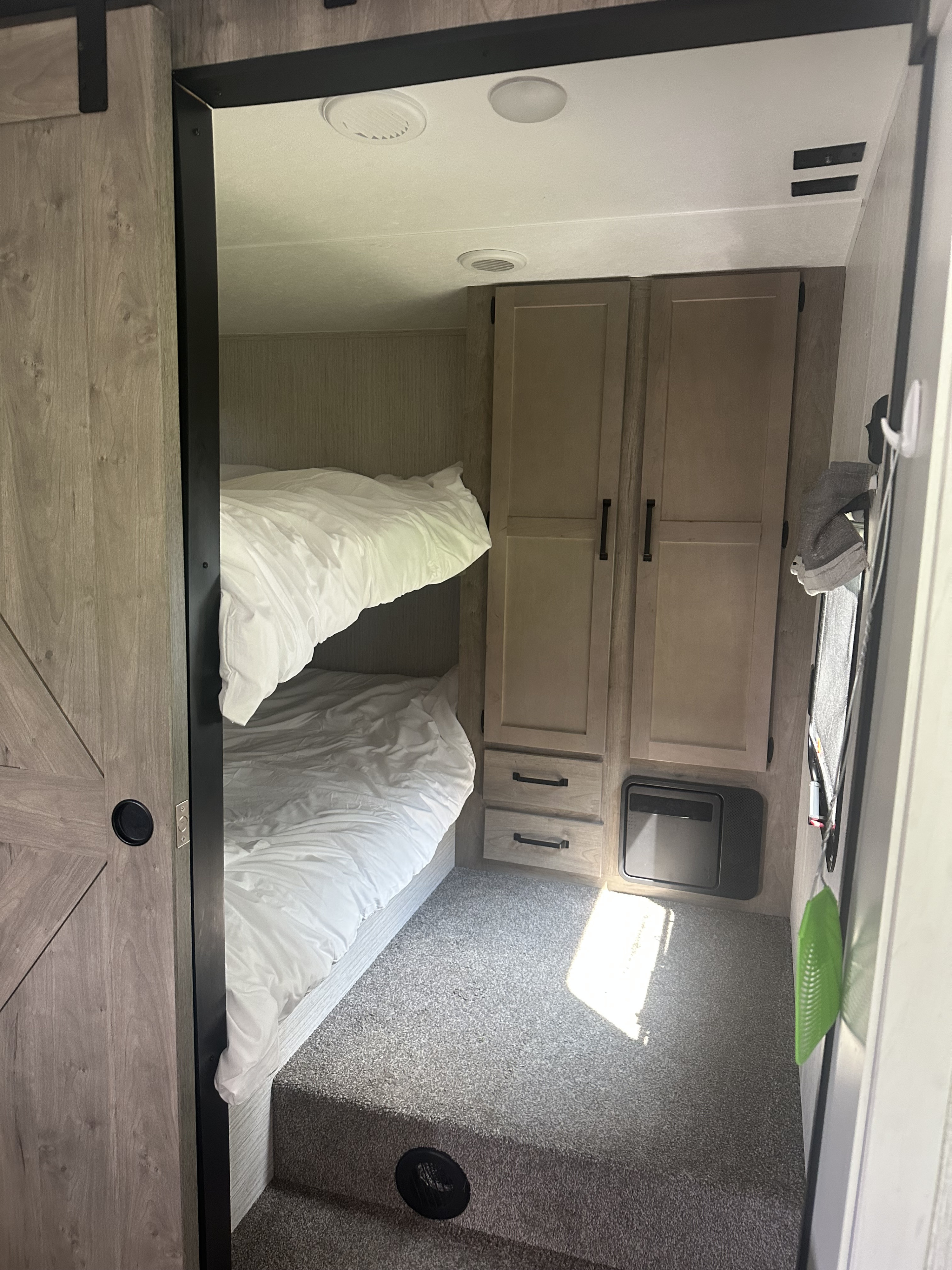 Cozy RV rental space featuring stacked bunk beds with white bedding, built-in cabinets, and carpeted floor.. Forest River Palomino Puma 2022
