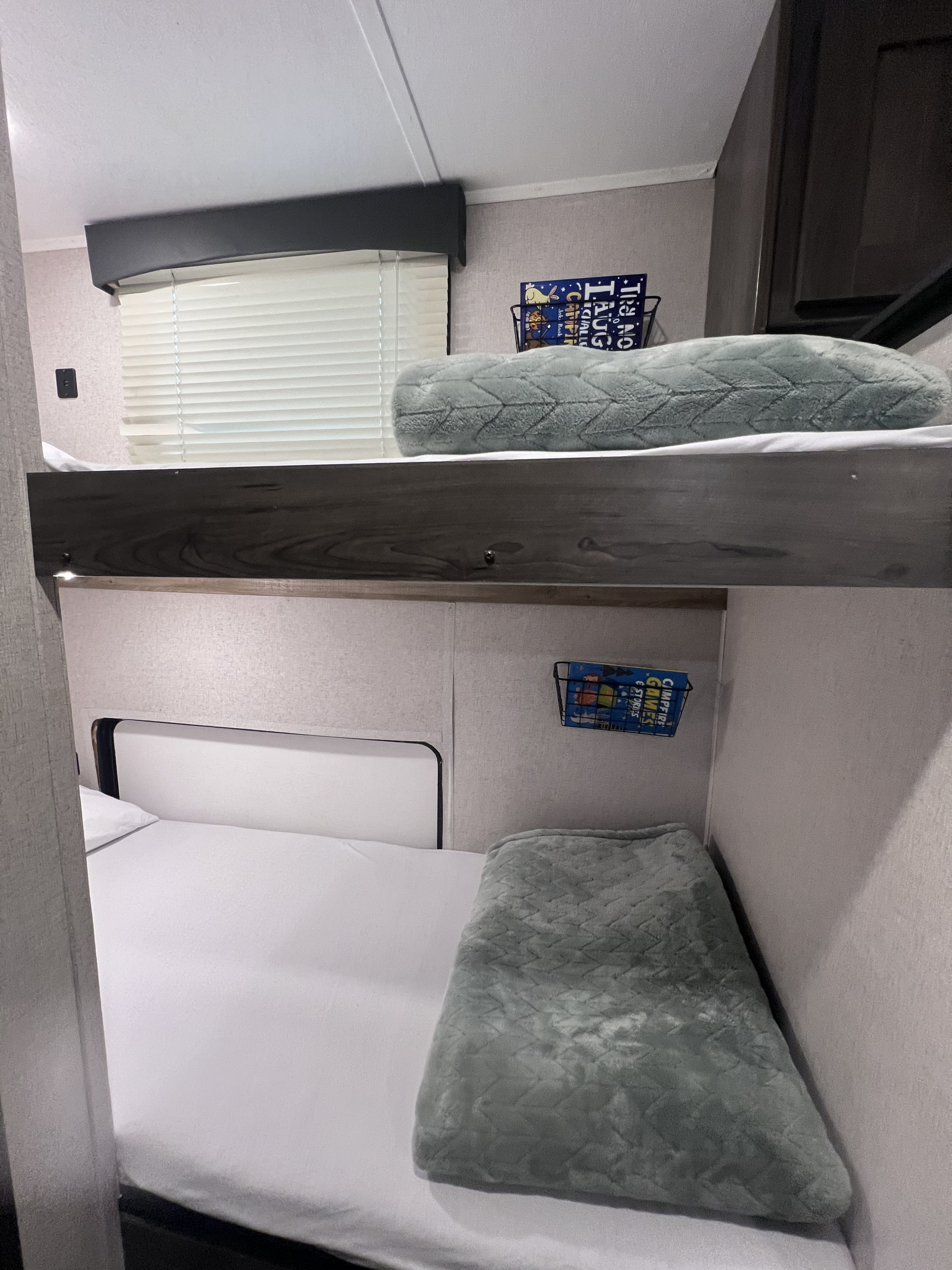 An RV rental's cozy bunk beds. White sheets, soft pillows & blankets, plus storage pockets for comfy sleeping.. Coachmen Viking Saga 17BH 2021