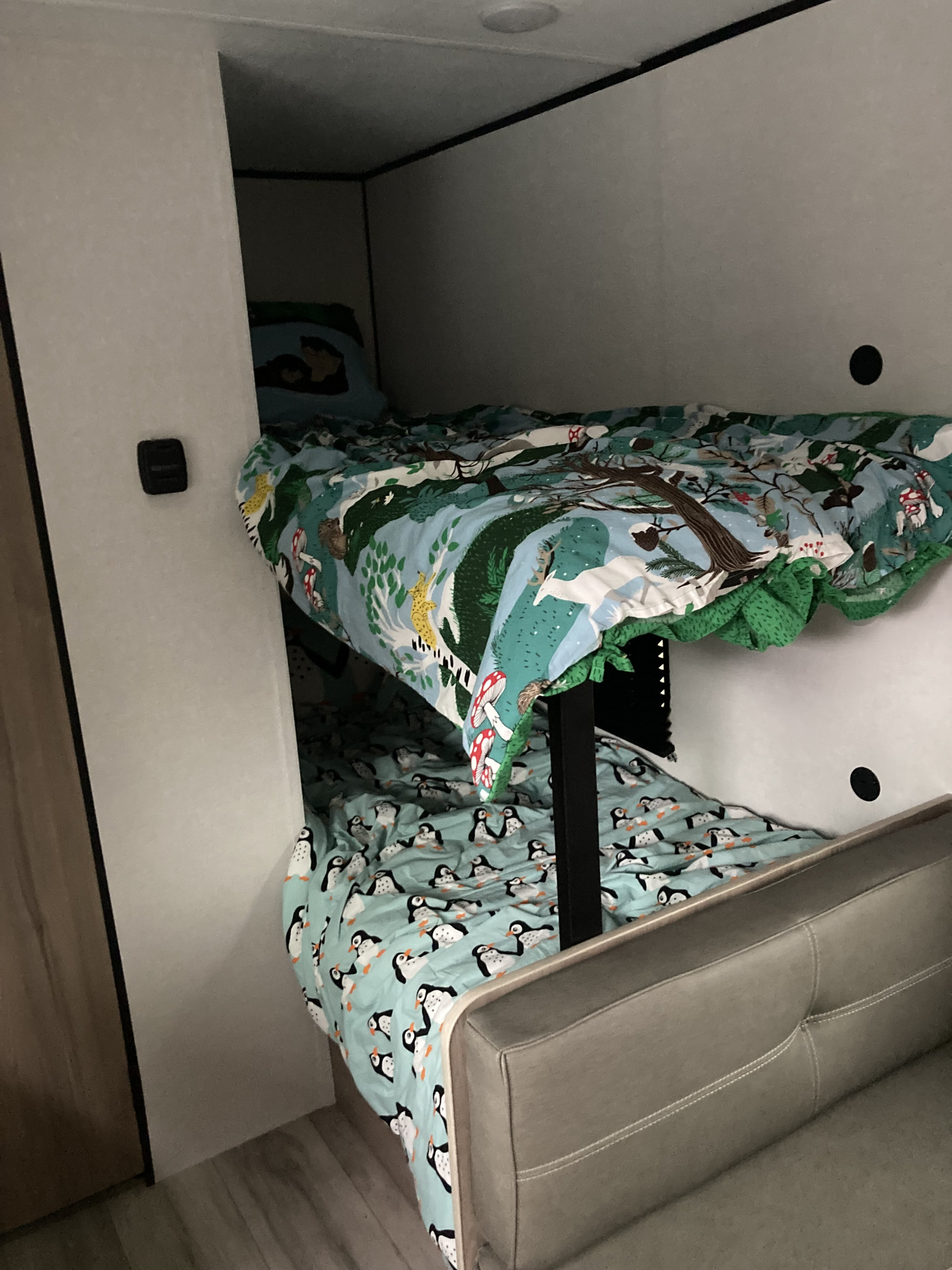 Cozy bunk beds in an RV rental, featuring whimsical forest and penguin bedding, great for family adventures on the road.. Keystone Coleman 17b 2025