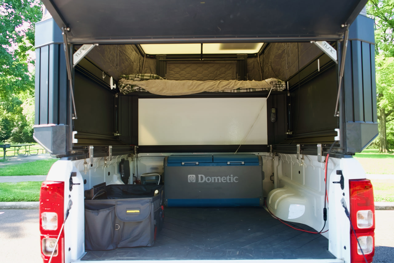 Inside a white pickup truck's open camper, showing a bed, Dometic fridge, & storage. Ideal for an RV rental camping adventure.. Ford Ranger 2300 Cc 2021