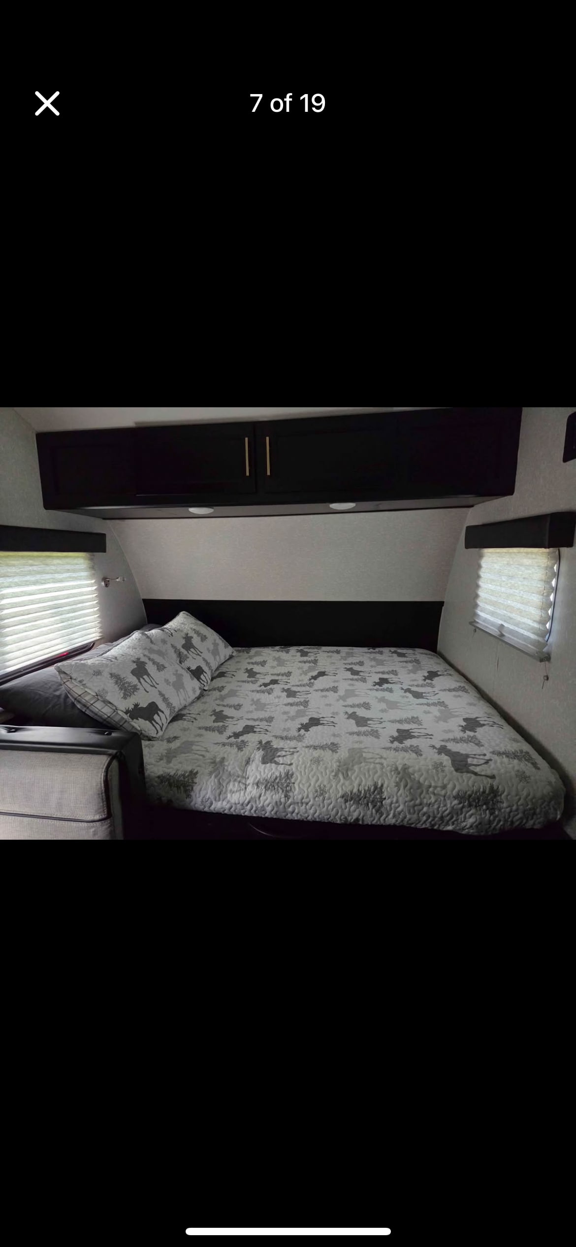 Comfortable RV rental bedroom with a bed, moose-patterned bedding, overhead storage, and side windows.. Forest River Cherokee Wolf Pup Black Label 2022