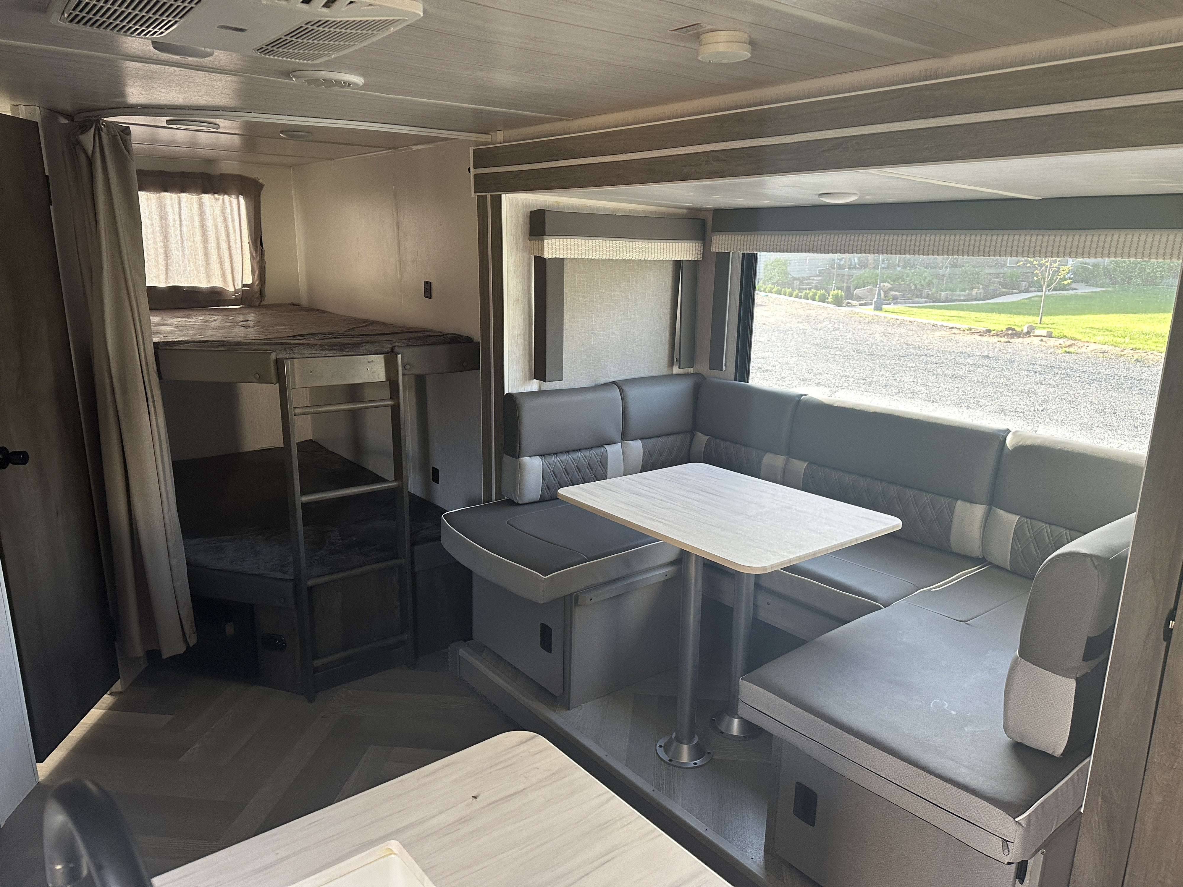 Spacious RV rental interior featuring a bunk bed area with ladder and a U-shaped dinette with a table.. Forest River Salem Cruise Lite 2022