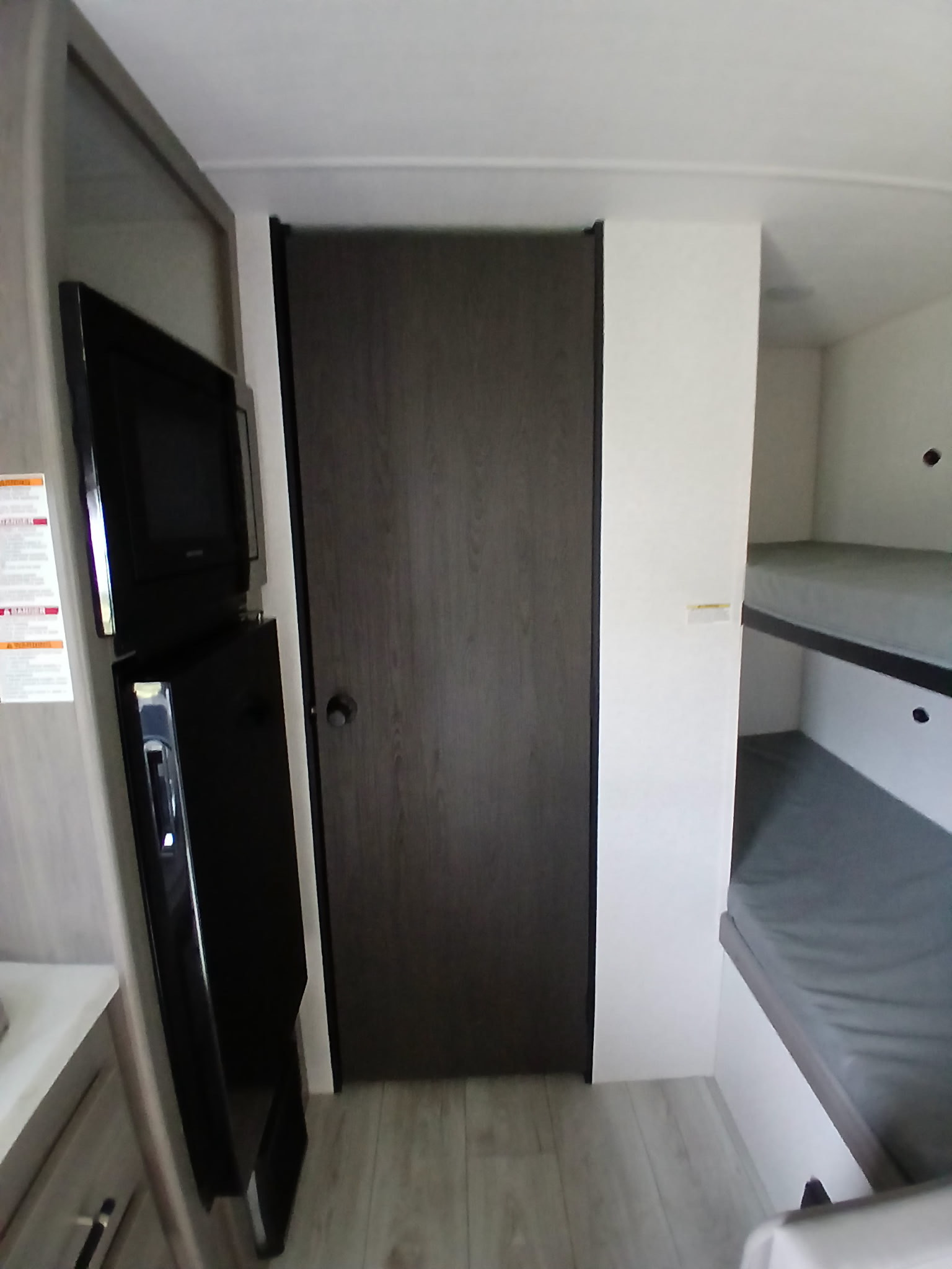 Explore this RV rental interior: built-in TV, fridge, an interior door, and comfortable bunk beds for travelers.. Keystone Hideout Sport 175BH 2025