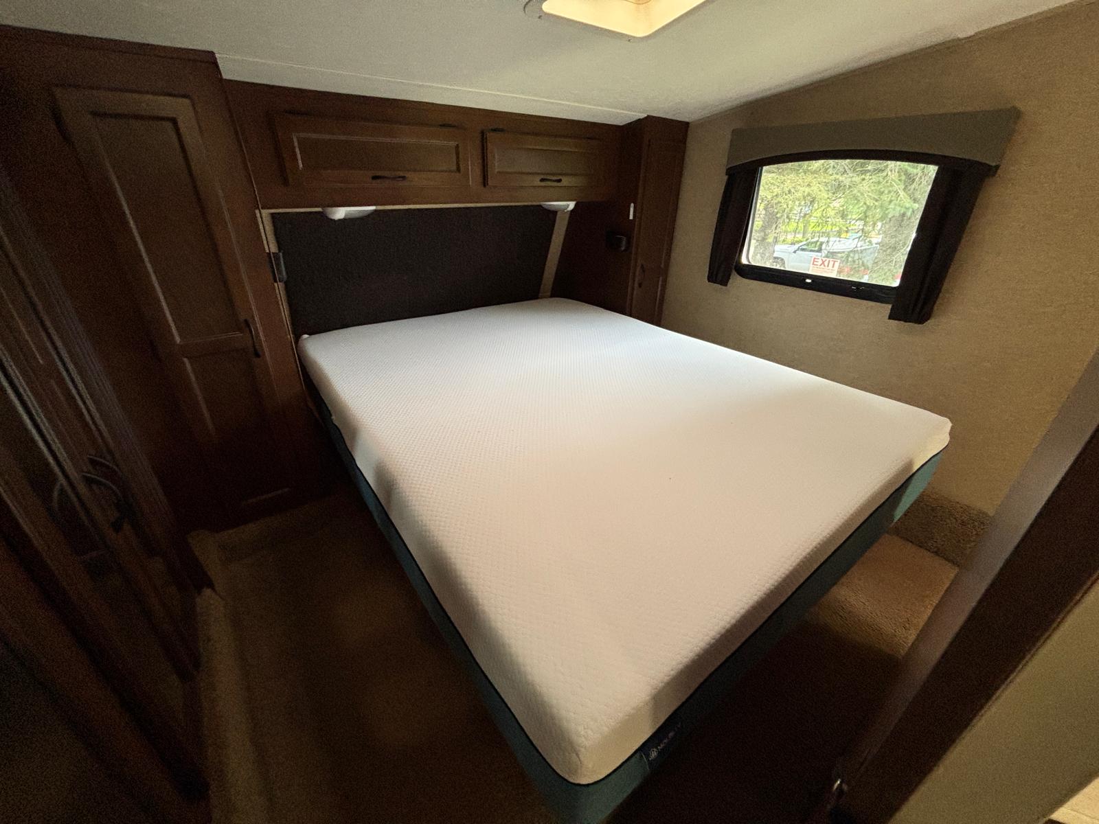 RV rental: Clean, comfortable bedroom features a white mattress, dark wood cabinets, and a window with a view.. Jayco Eagle Touring 2014