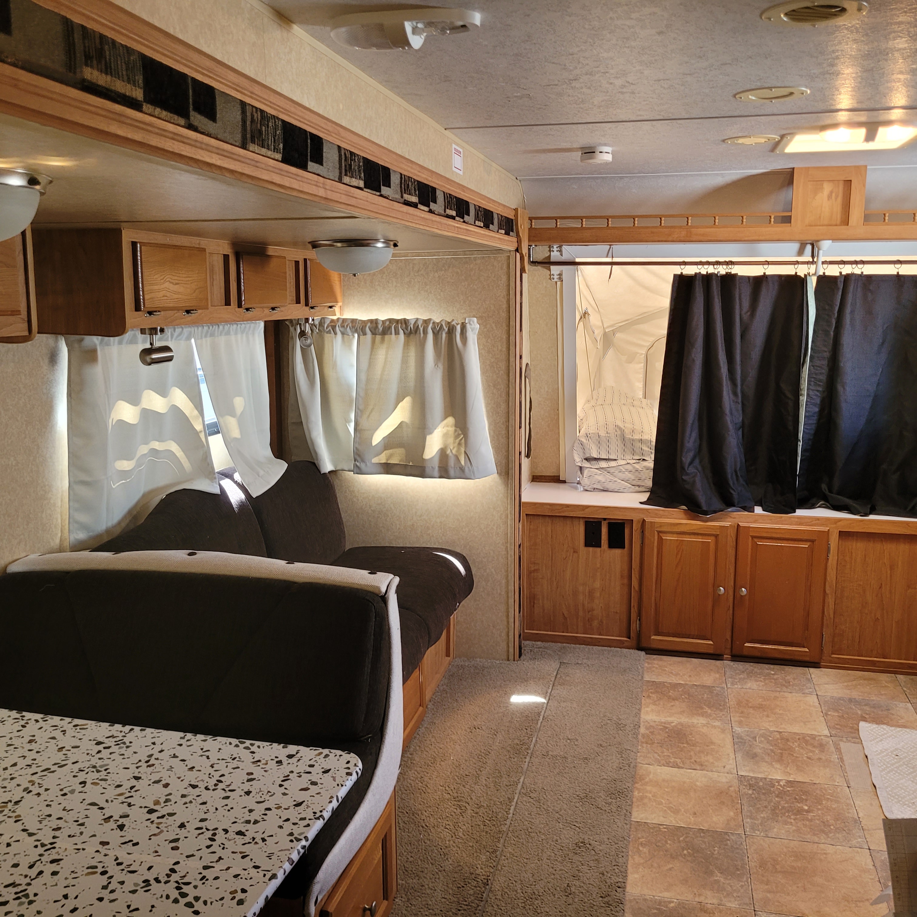 Spacious RV rental interior with cozy dinette, ample storage, and a private pop-out bed area, perfect for adventures.. Forest River Rockwood Roo 2011