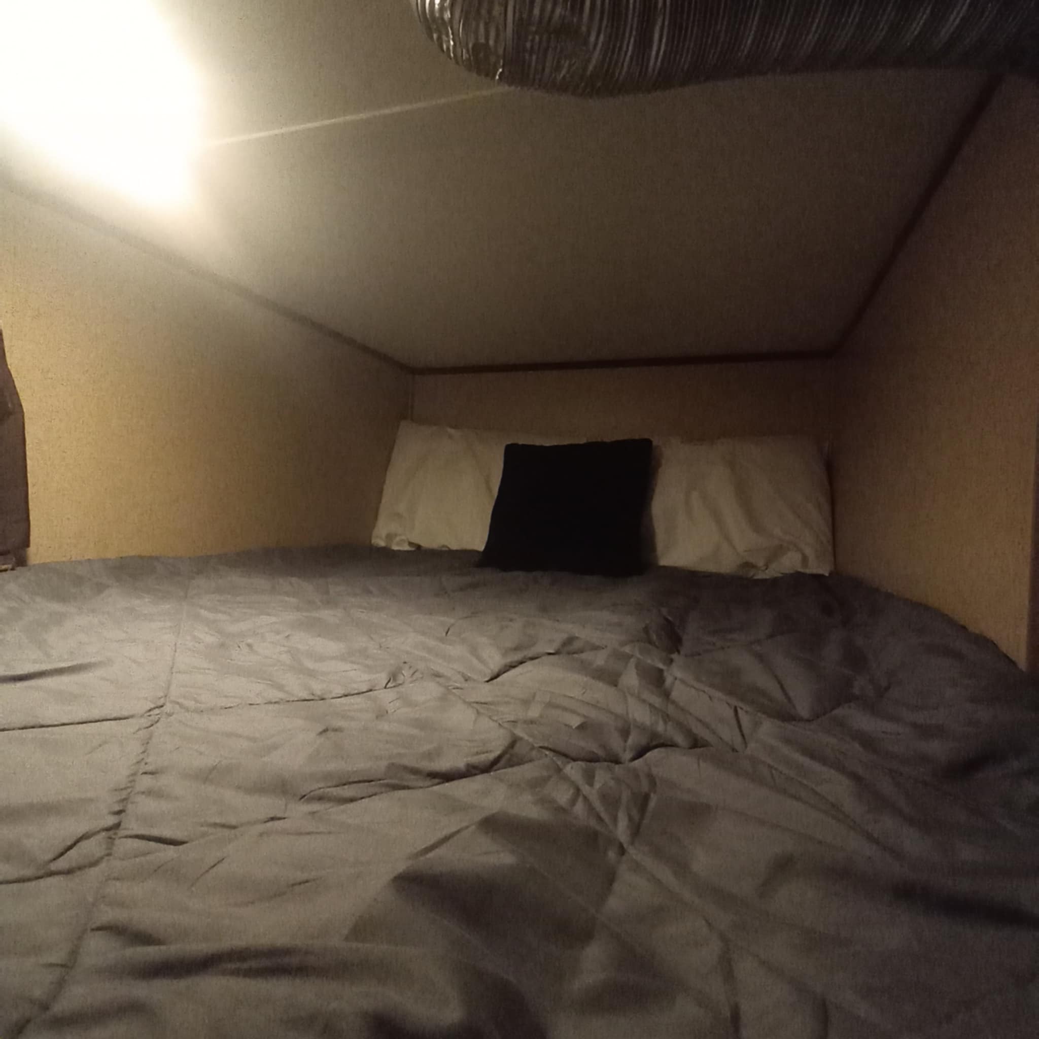 An RV rental's cozy bed with white/black pillows & gray comforter. Brightly lit sleeping area.. Full size bed lower Bunkhouse.. Jayco Jay Flight SLX 2016