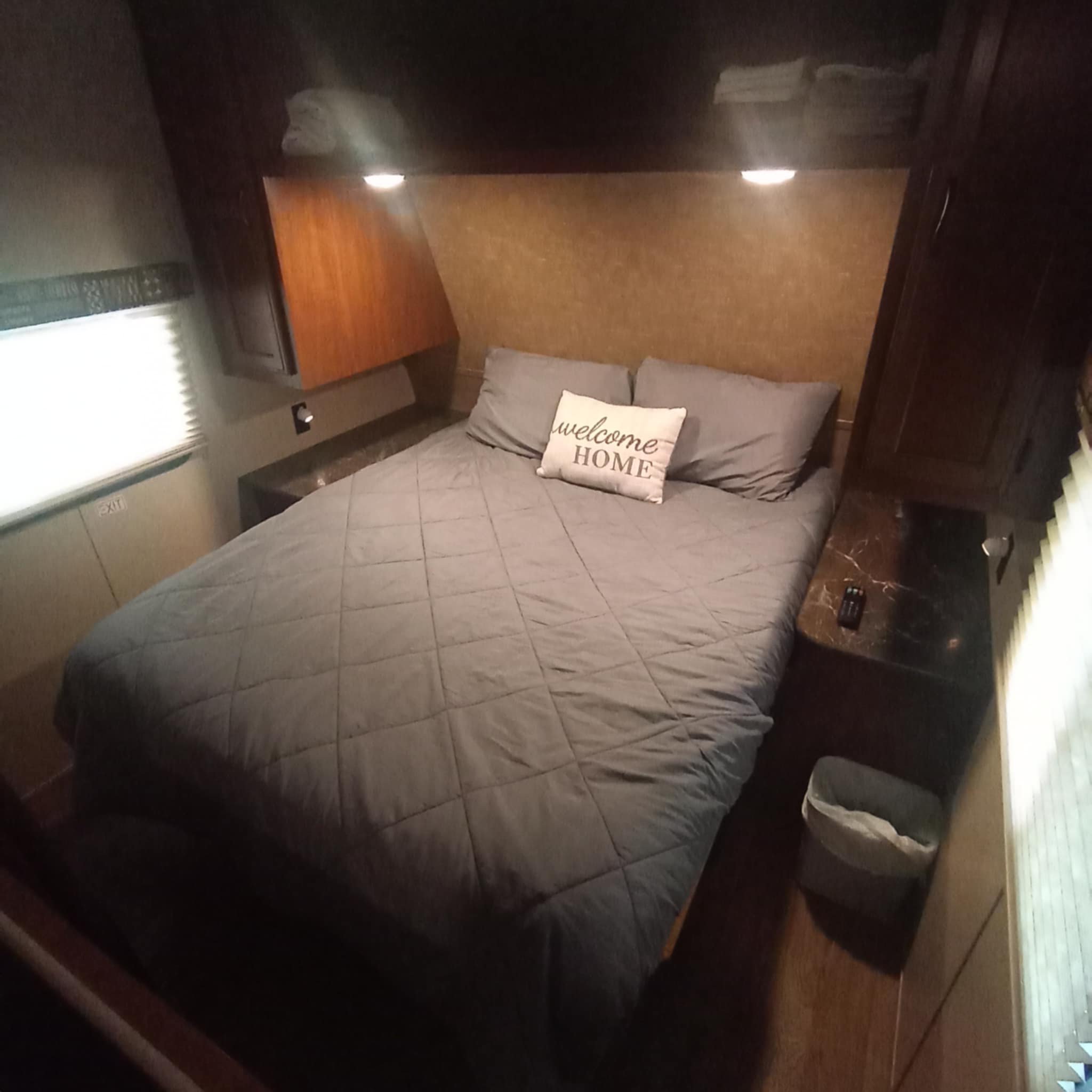 RV rental Queen bedroom interior: a plush bed with "welcome HOME" pillow, dual reading lights, and 2 wardrobe closets. Extra overhead storage.. Jayco Jay Flight SLX 2016