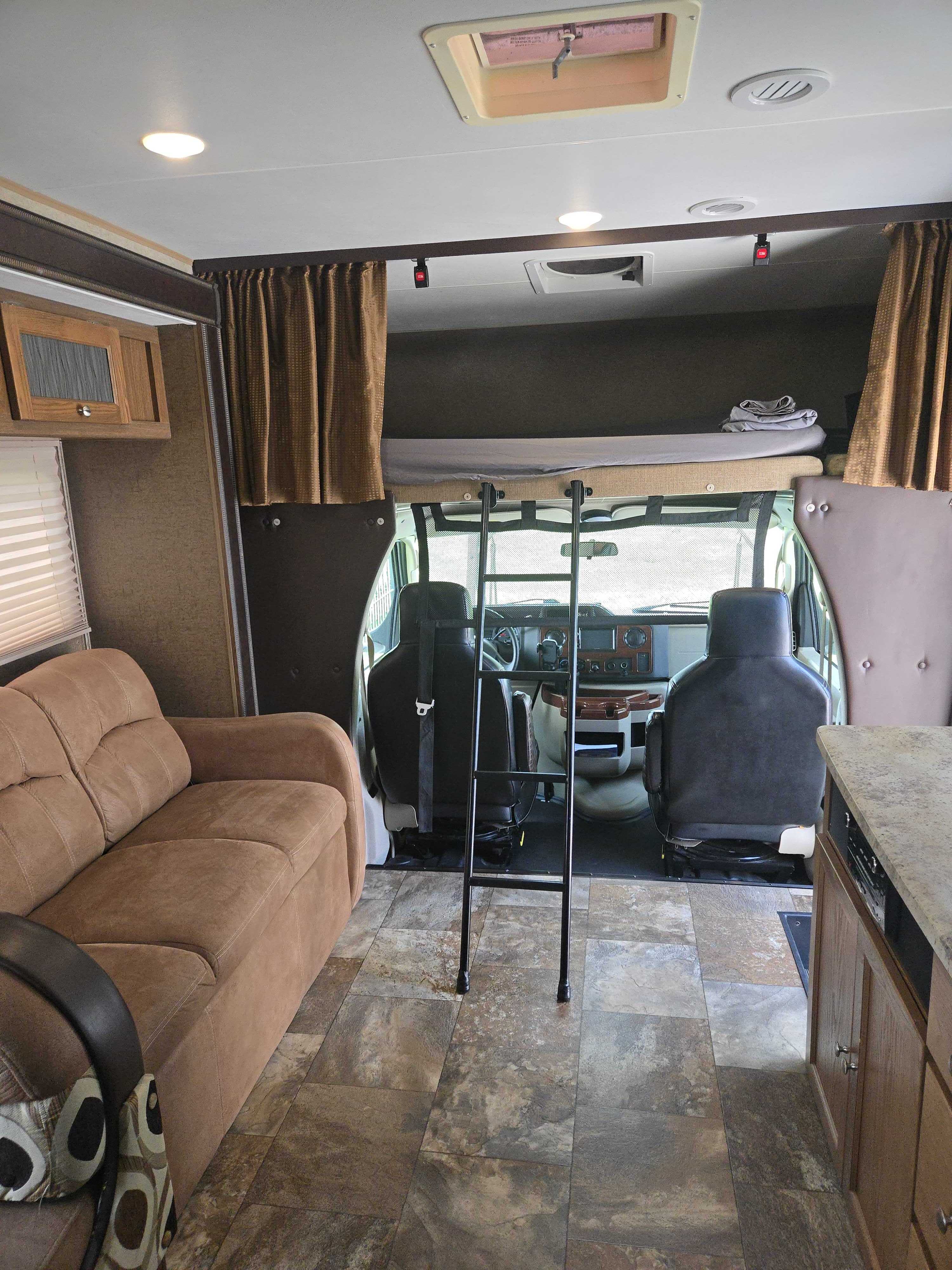 Spacious RV rental interior with sofa, kitchen counter, overhead bunk bed, and a ladder for access.. Forest River Coachmen Leprechaun 2017