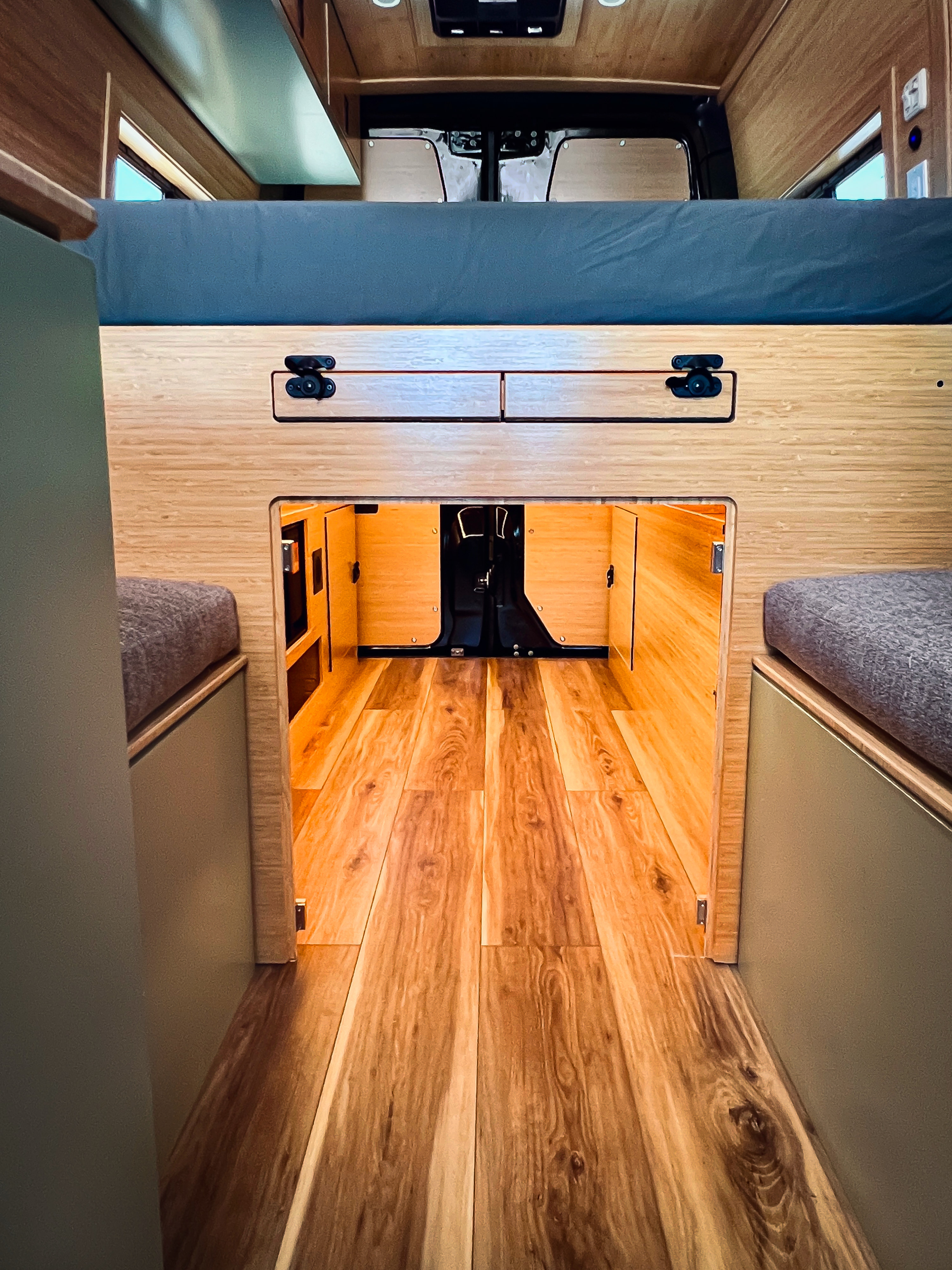 An inviting RV rental interior view: comfortable bed, clever wooden storage, and bright, clean flooring for your next adventure.. Mercedes-Benz Sprinter 2500 2024