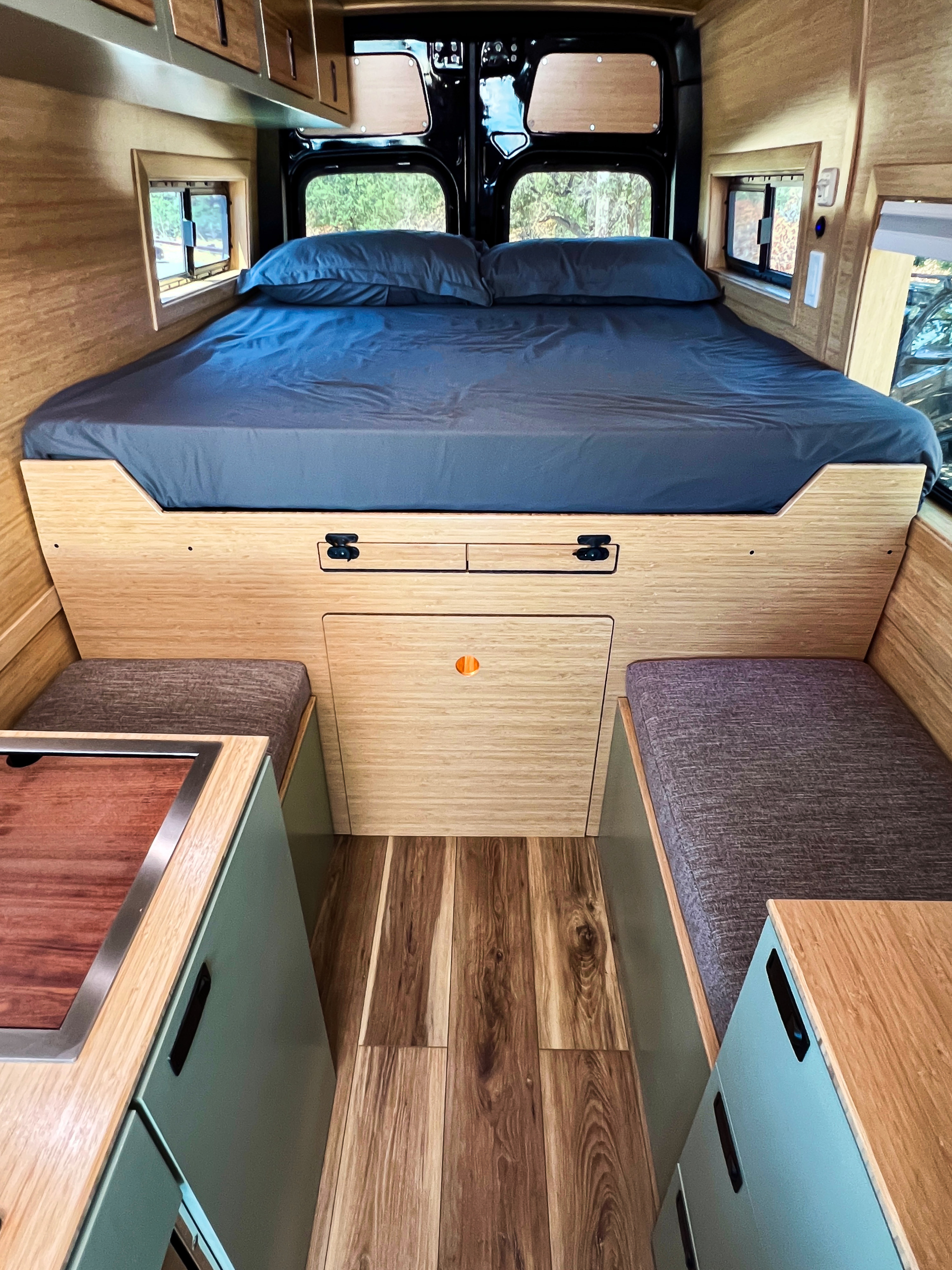 This RV rental interior has a comfortable bed, wood-paneled walls, a kitchenette, and efficient storage for your travels.. Mercedes-Benz Sprinter 2500 2024