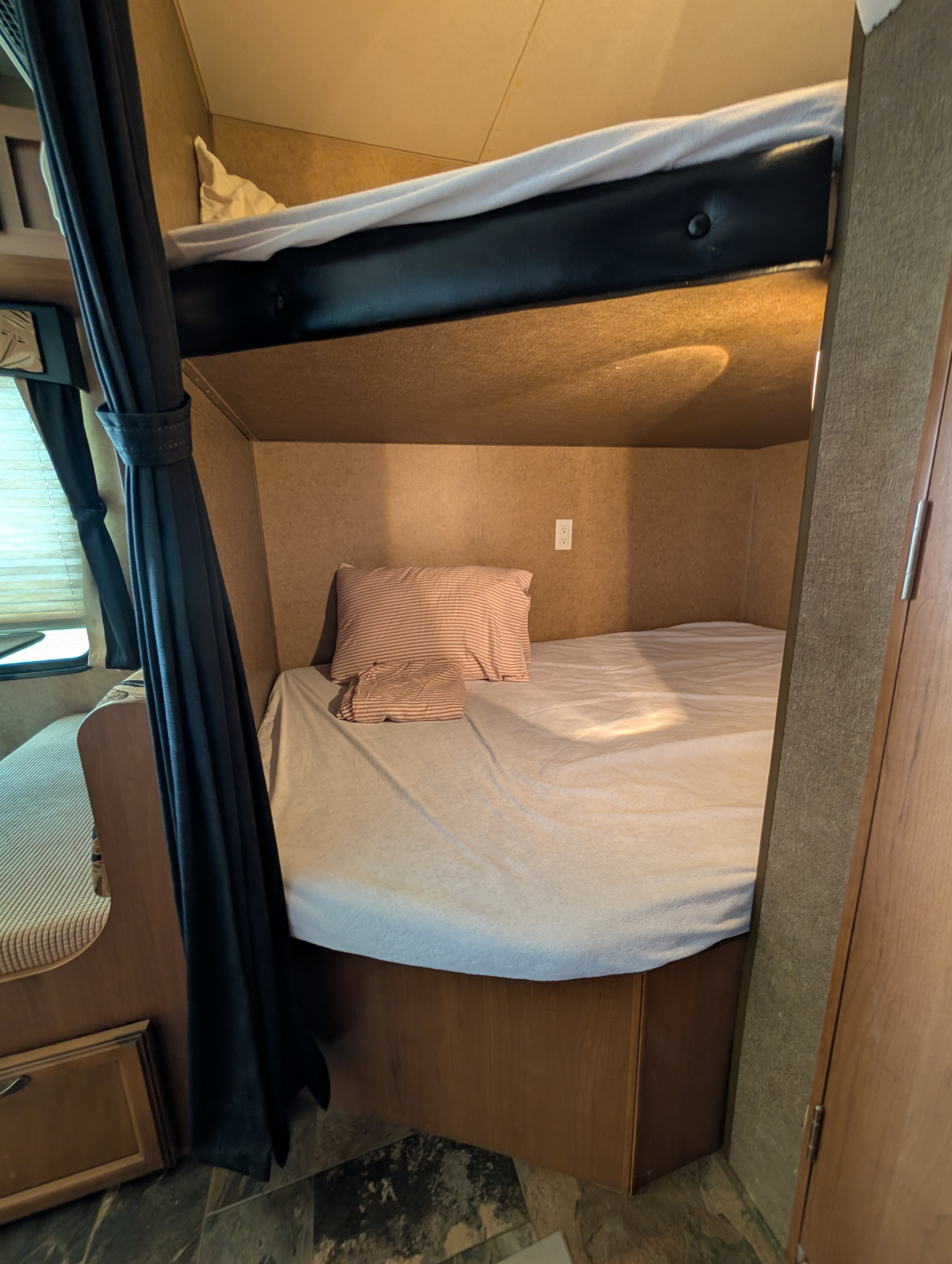 RV rental interior: A cozy bunk bed setup with upper & lower bunks, fresh bedding, curtains, and an electrical outlet.. Starcraft Autumn Ridge 2013