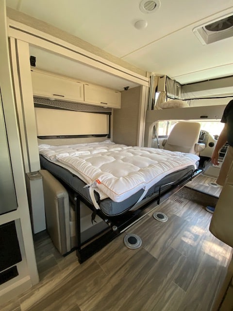 Explore this RV rental's cozy interior, featuring a lowered drop-down bed, overhead cabinets, and durable flooring.. Thor Axis 2023
