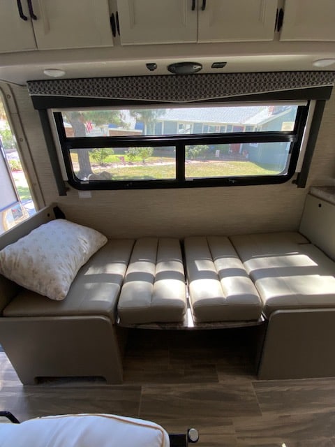 RV rental: Convertible dinette/bed with light cushions, large window showing outdoor view.. Thor Axis 2023