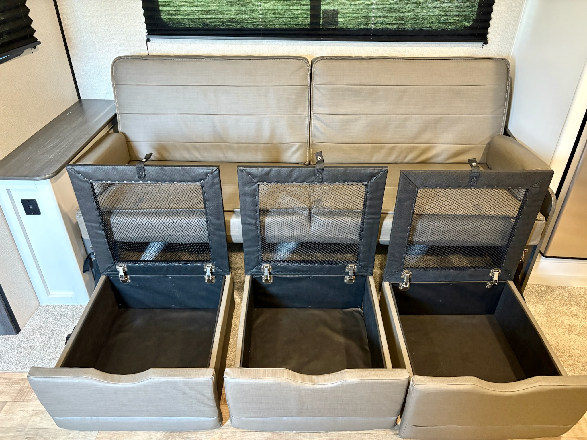 RV rental: Beige sofa and three open storage ottomans with mesh lids provide versatile seating and smart organization for travelers.. Keystone RV Hideout 2022