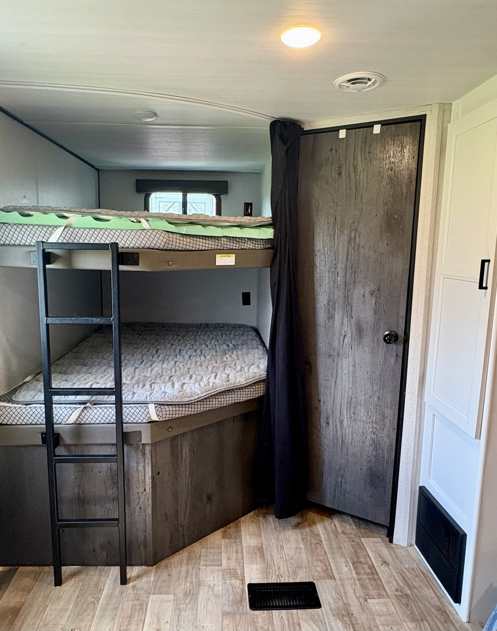 Inside an RV rental: bunk beds with ladder, door, and bright ceiling light.. Keystone RV Hideout 2022