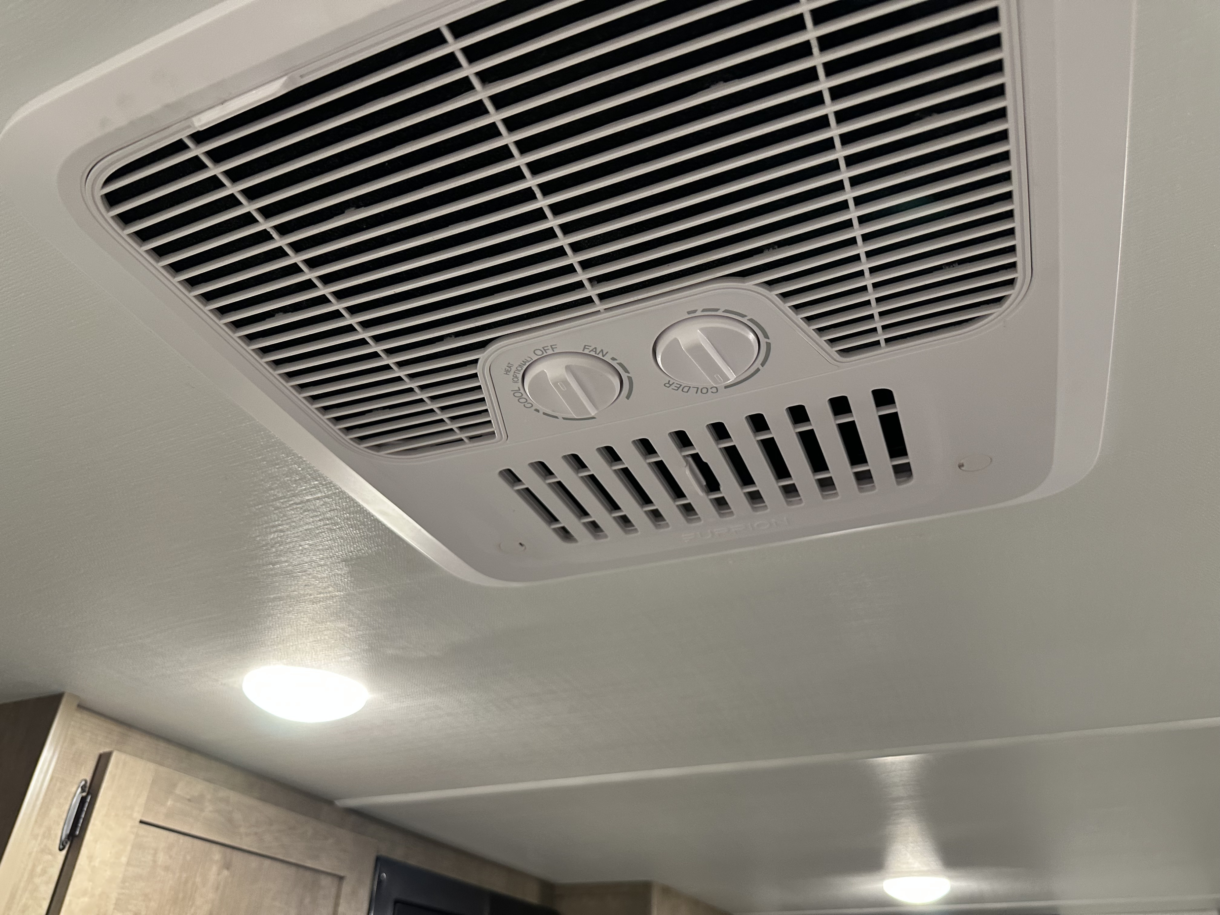 White Furrion RV air conditioner with fan & temperature controls mounted on a textured ceiling in an rv rental.. Keystone RV Springdale 2025