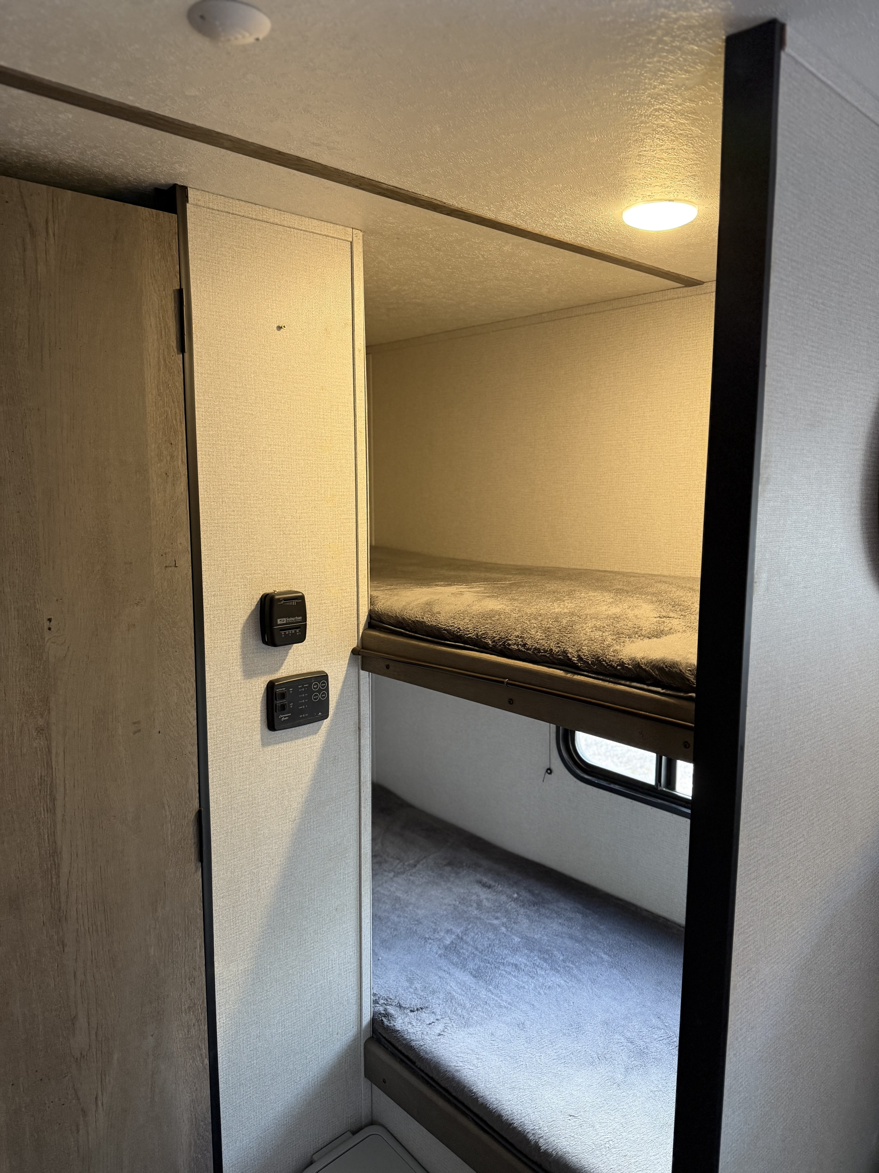 RV rental bunk beds: a cozy, compact sleeping area with essential controls and a window. Perfect for family trips.. Keystone RV Springdale 2022