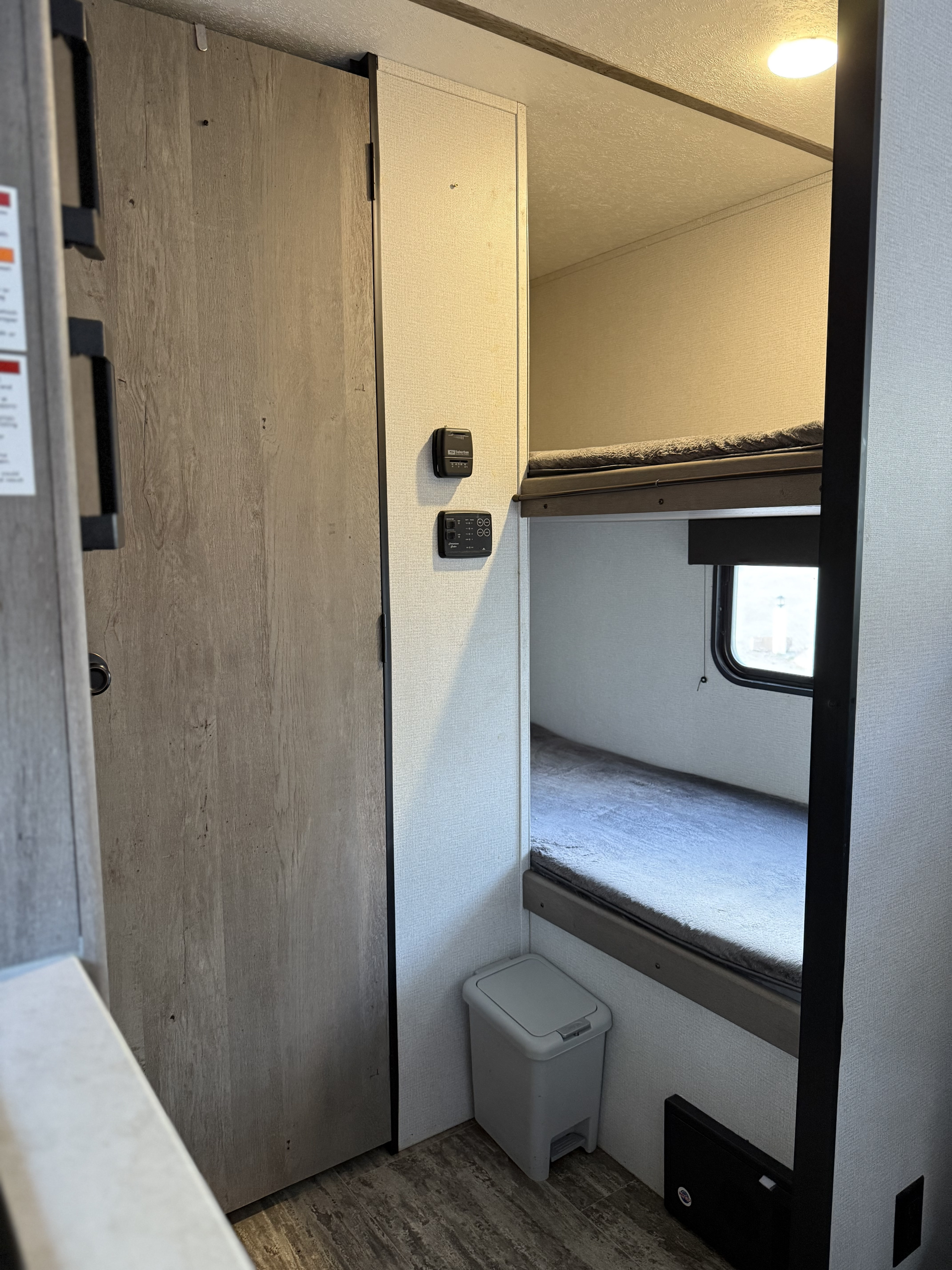 Step into this RV rental, revealing a smart interior with bunk beds, a closet, and wall-mounted controls, designed for efficient living.. Keystone RV Springdale 2022