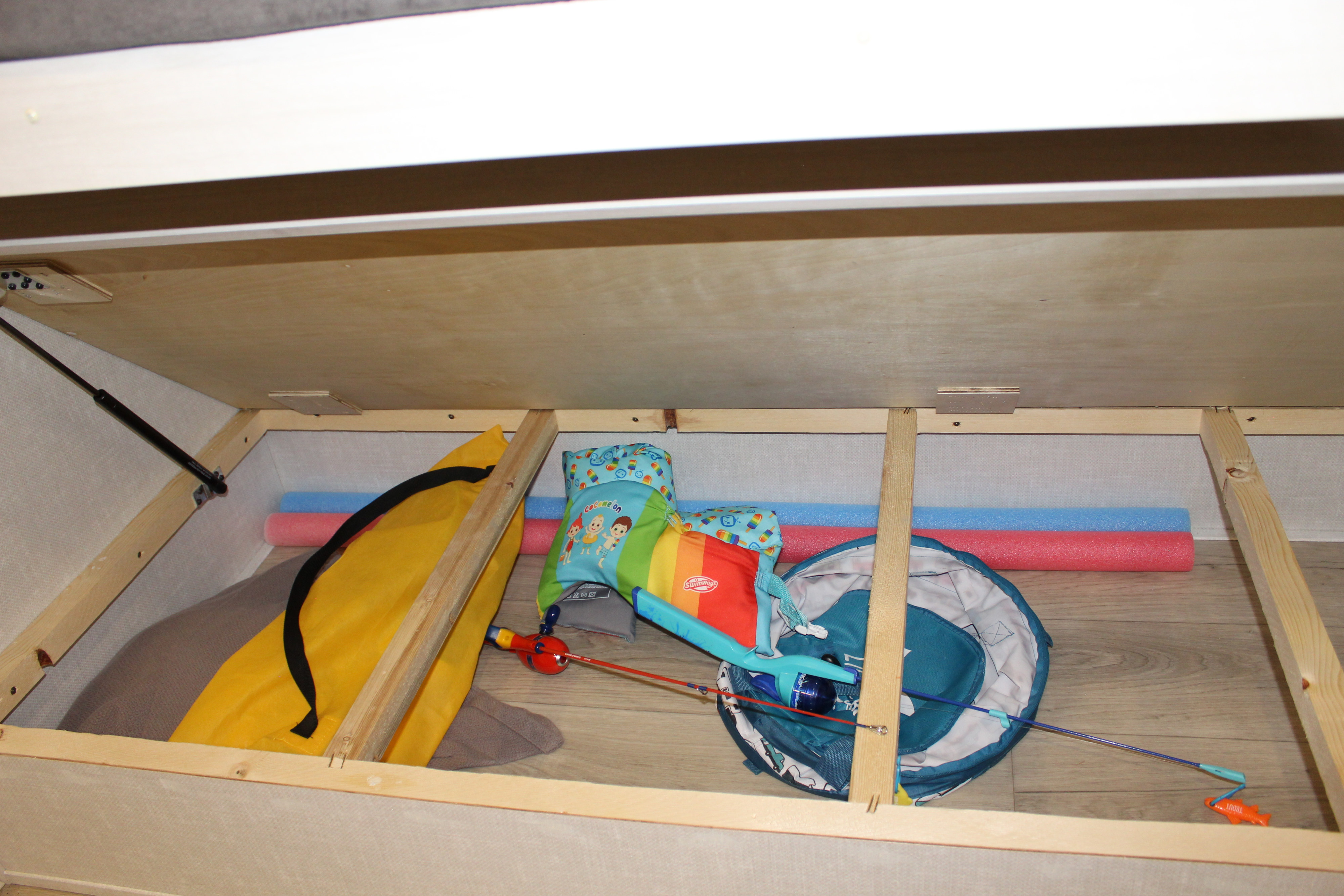 RV rental: Under-bed storage reveals pool noodles, swim vest, toys, and a gas strut for efficient space use.. Surveyor Legend 303BHLE 2025
