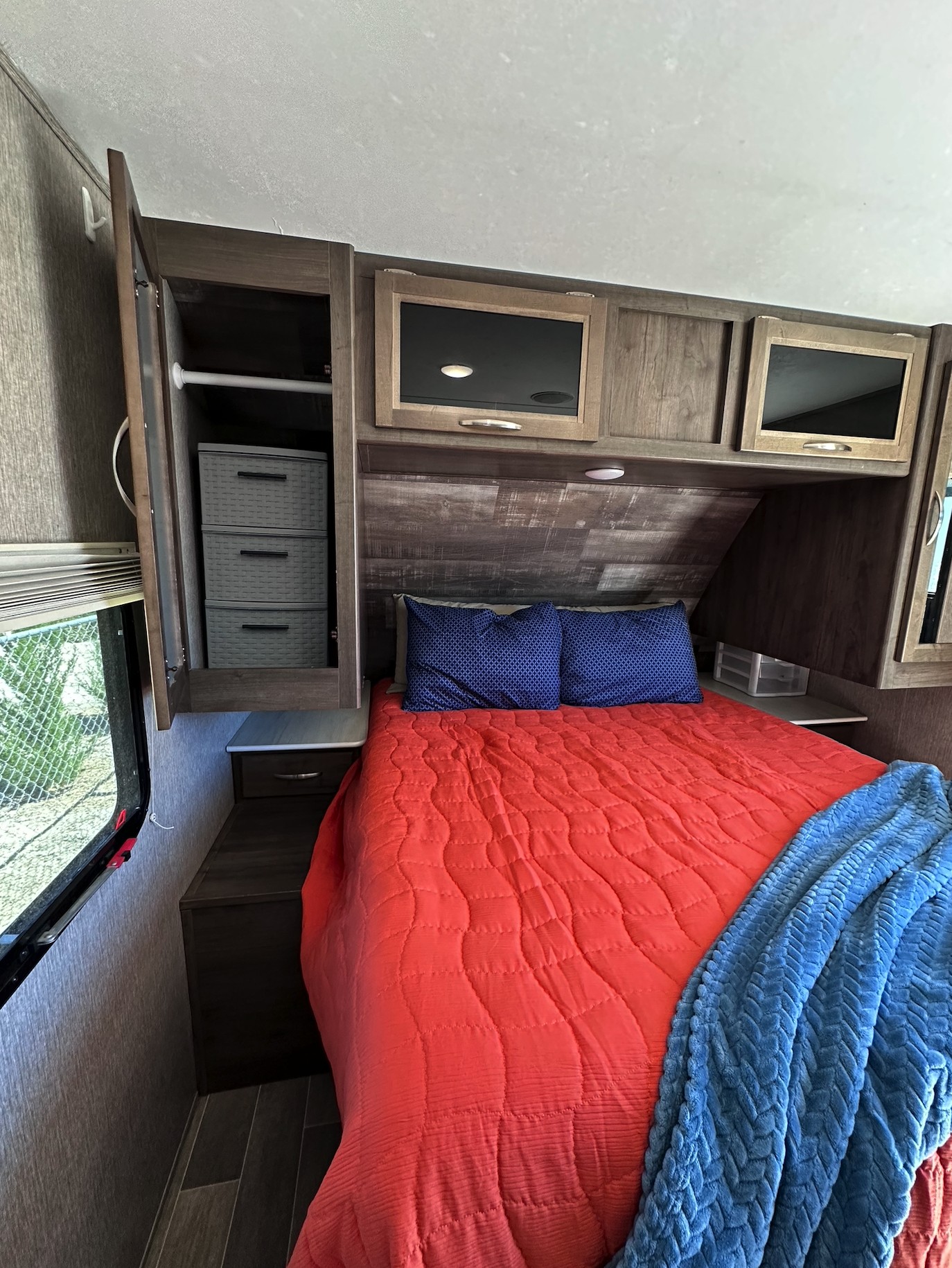 Inside an RV rental: a compact bedroom featuring a bed, ample overhead storage, and a built-in wardrobe.. Coleman 1805RB 2020