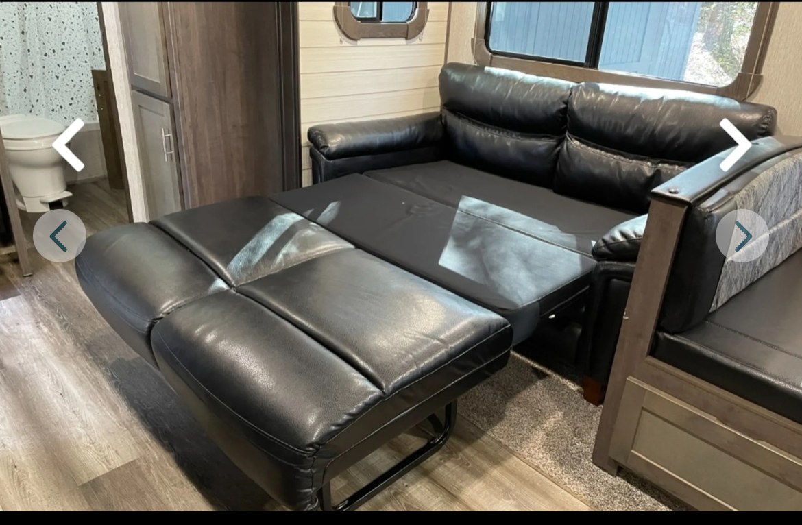 RV rental: Black leather pull-out sofa bed inside a compact RV interior, with a bathroom visible in the background.. Crossroads RV Sunset Trail Super Lite 2019