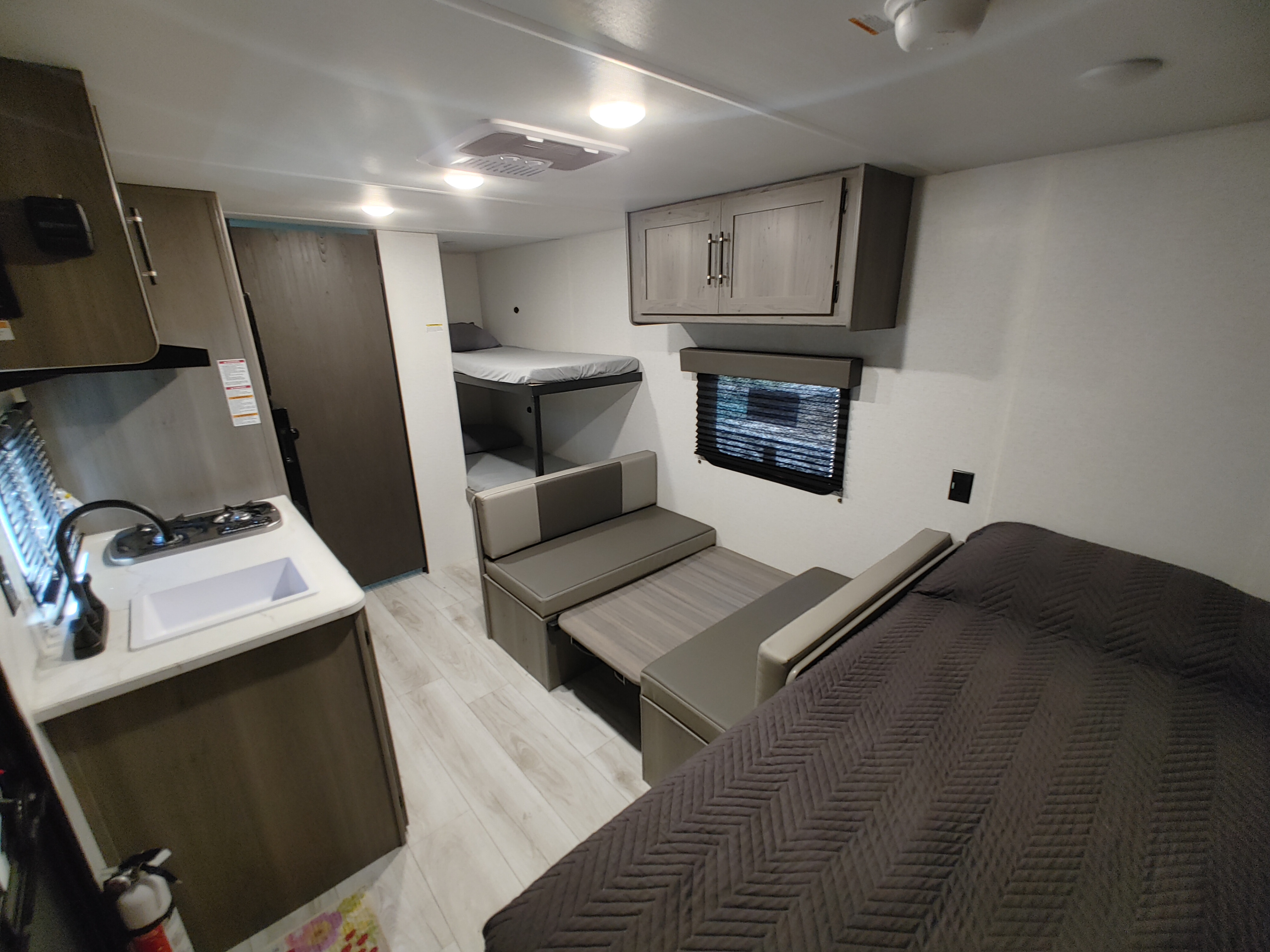 Spacious RV rental interior featuring a kitchen, comfy bunk beds, a main bed, and versatile dinette.. Keystone Hideout 175BH 2025