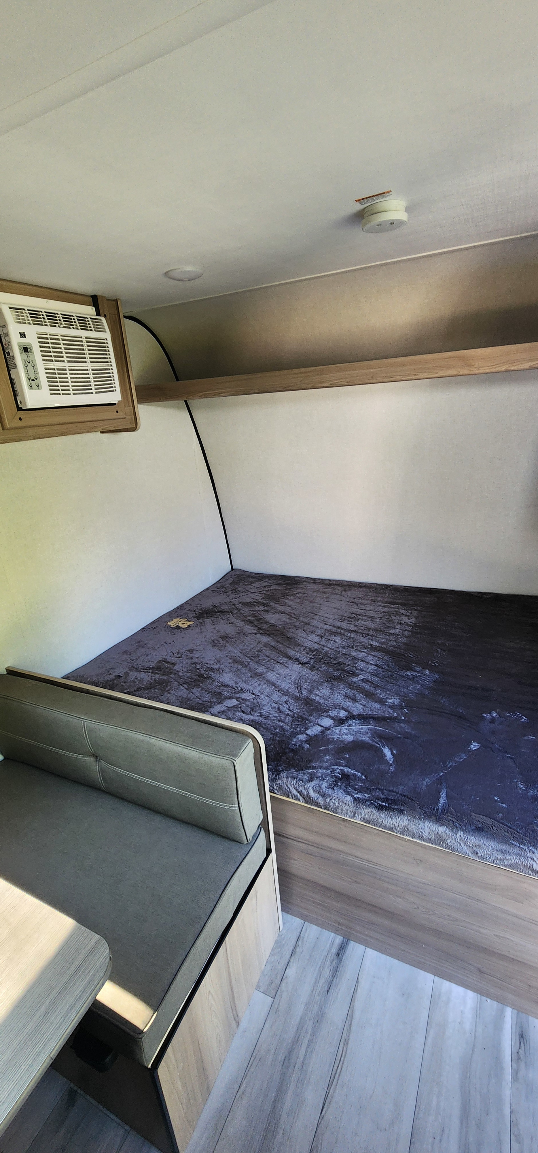 Compact RV rental interior featuring a bed, dinette, and AC unit, perfect for road trip comfort.. Coleman 17B 2026