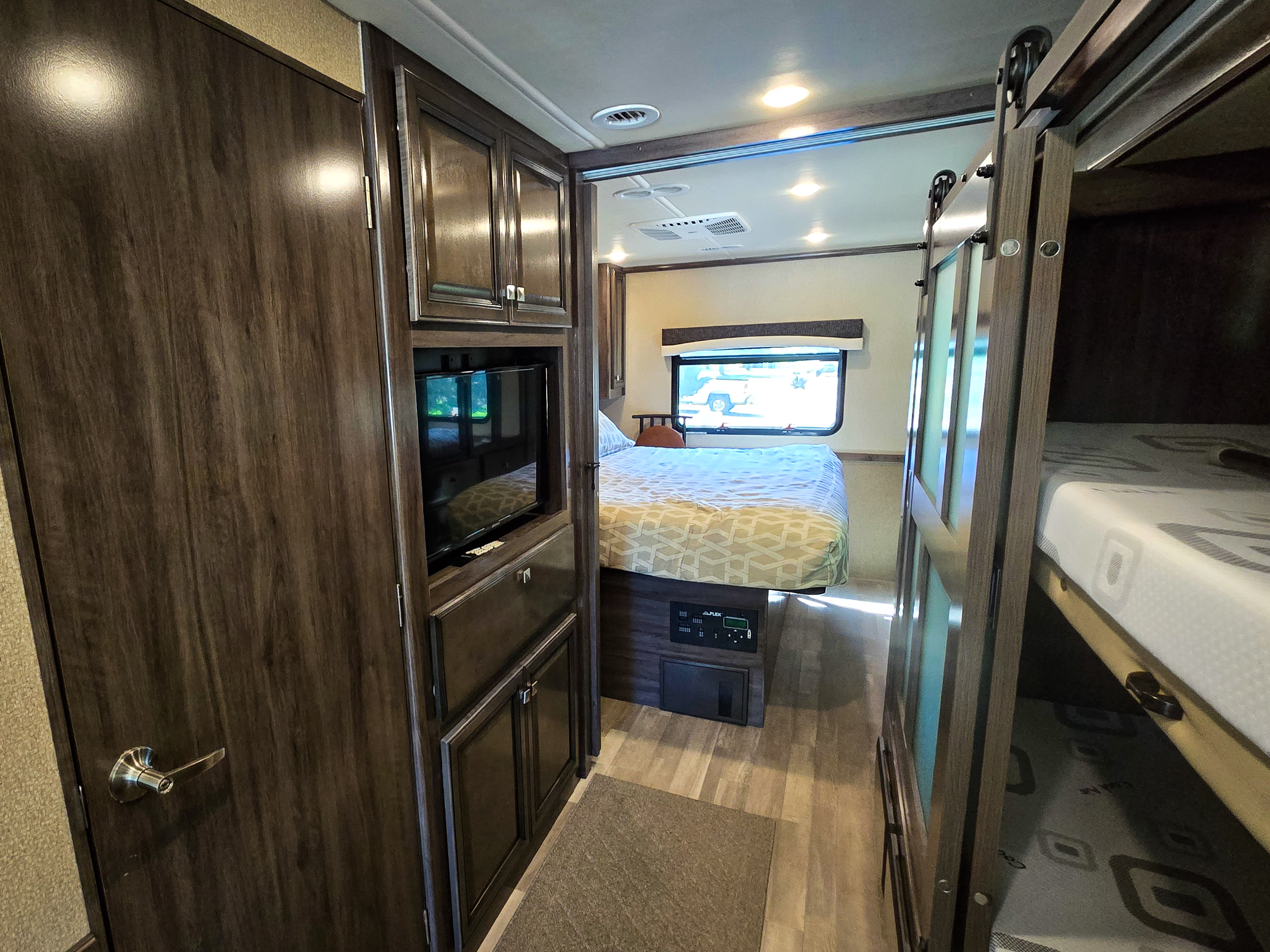 RV rental: Hallway reveals a bedroom (left) with bed and window, and bunk beds (right). Cabinets with TV built-in.. Flair-Fleetwood Flair-Fleetwood Motorhome 2019