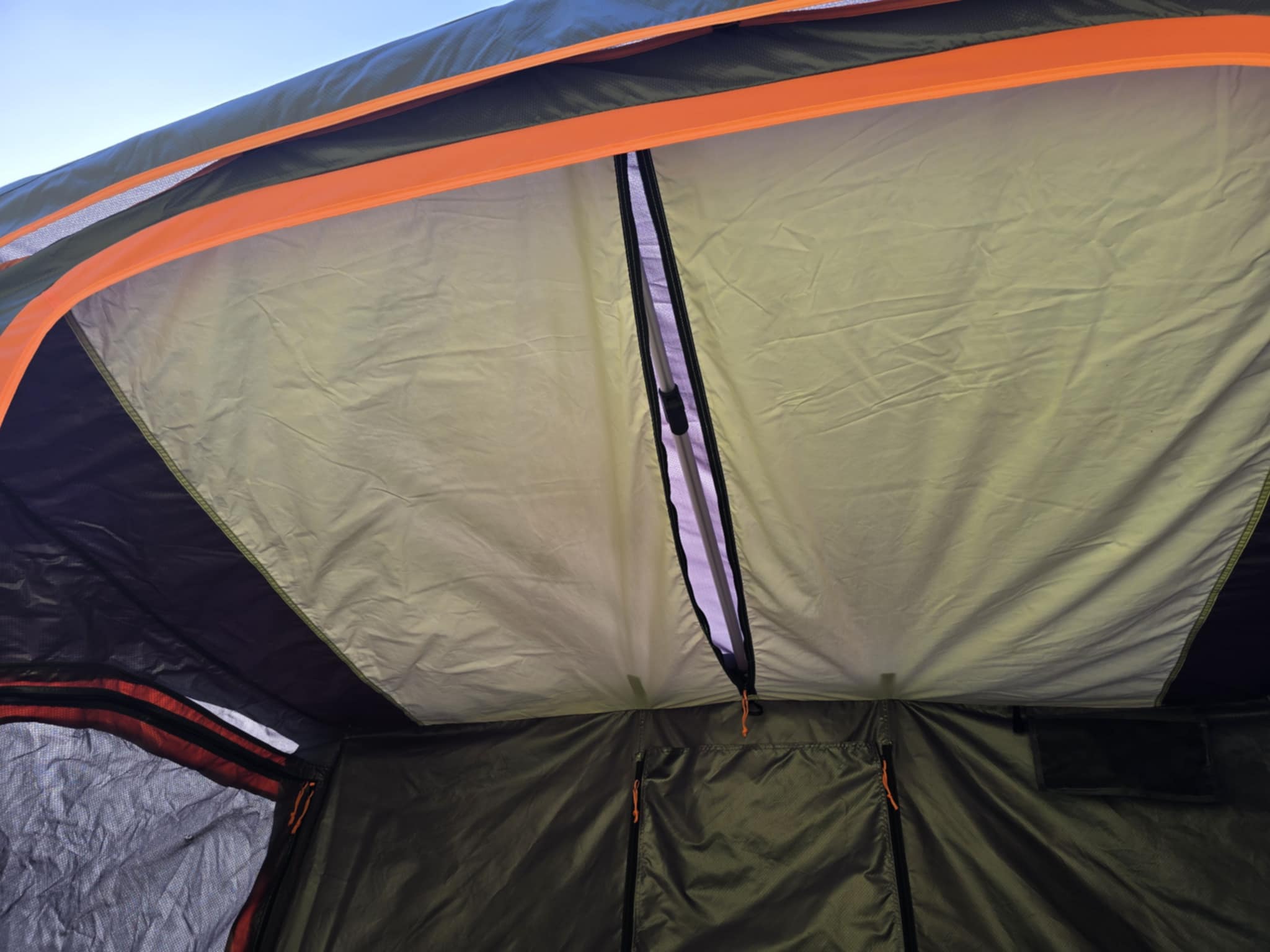 Interior of an RV rental camping tent, showing a light fabric ceiling with an open vent zipper, orange accents, and dark walls with pockets.. Nissan PRIMASTAR 2012