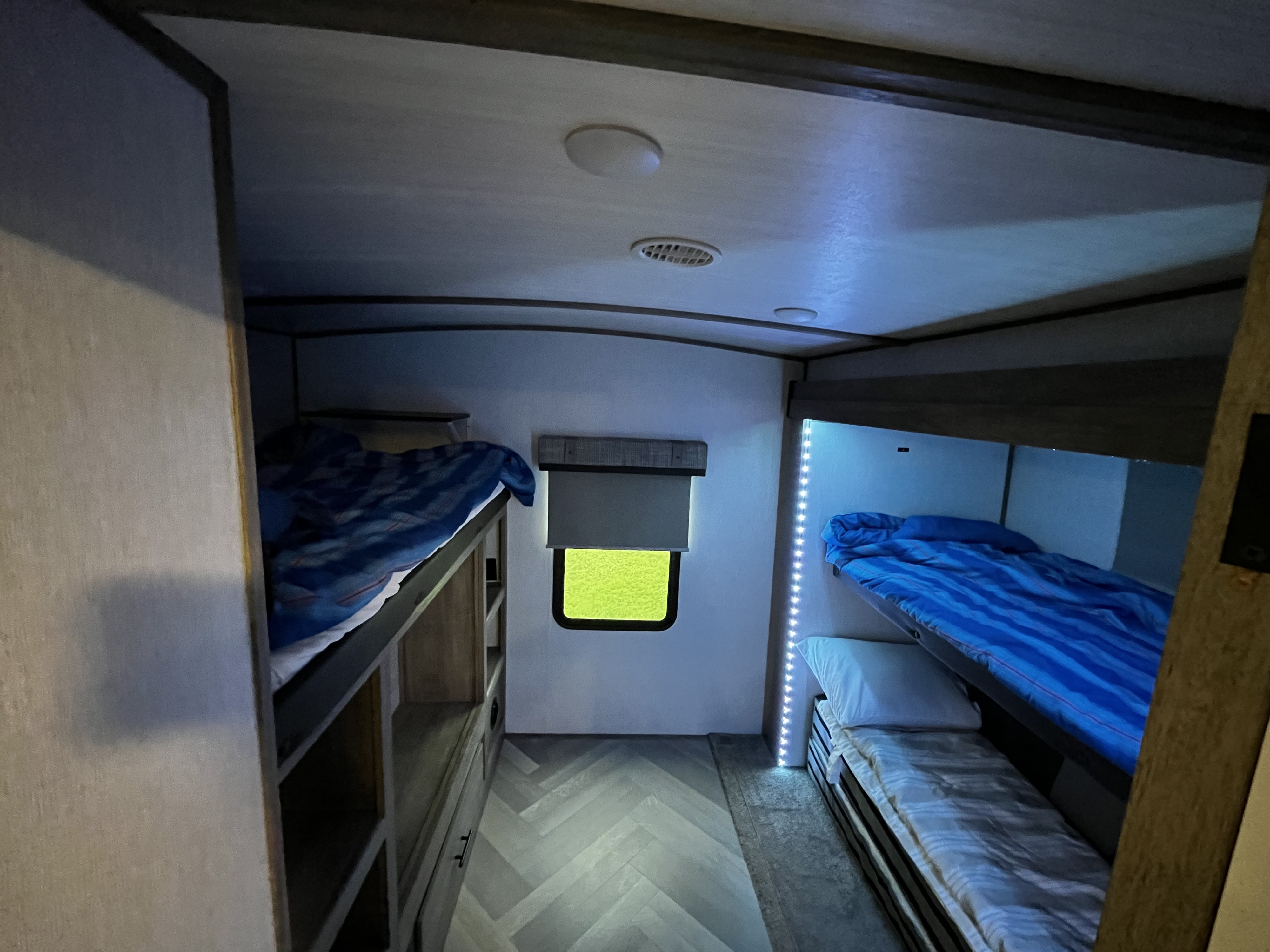 Cozy bunk beds inside an RV rental, perfect for family adventures. Bright green window and LED lighting add ambiance.. Forest River Salem Hemisphere 2022