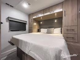 Experience comfort in this modern RV rental bedroom, featuring a large bed, built-in storage, and ambient lighting.. Grand Design Imagine XLS 2023