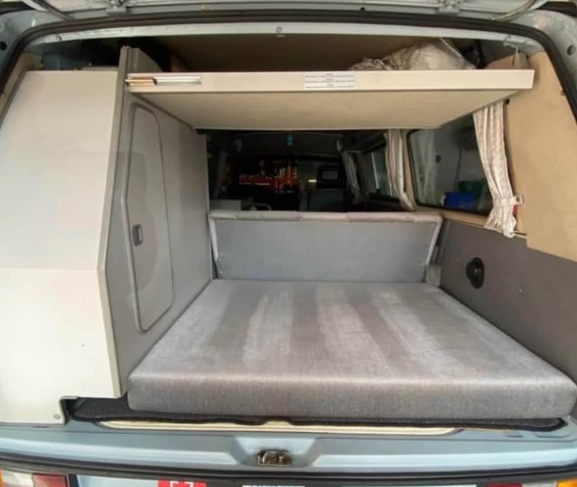 Inside a modern camper van: ready for rv rental trips. Features a comfy bed, built-in storage, and upper bunk.. Volkswagen T3 Westfalia 1987