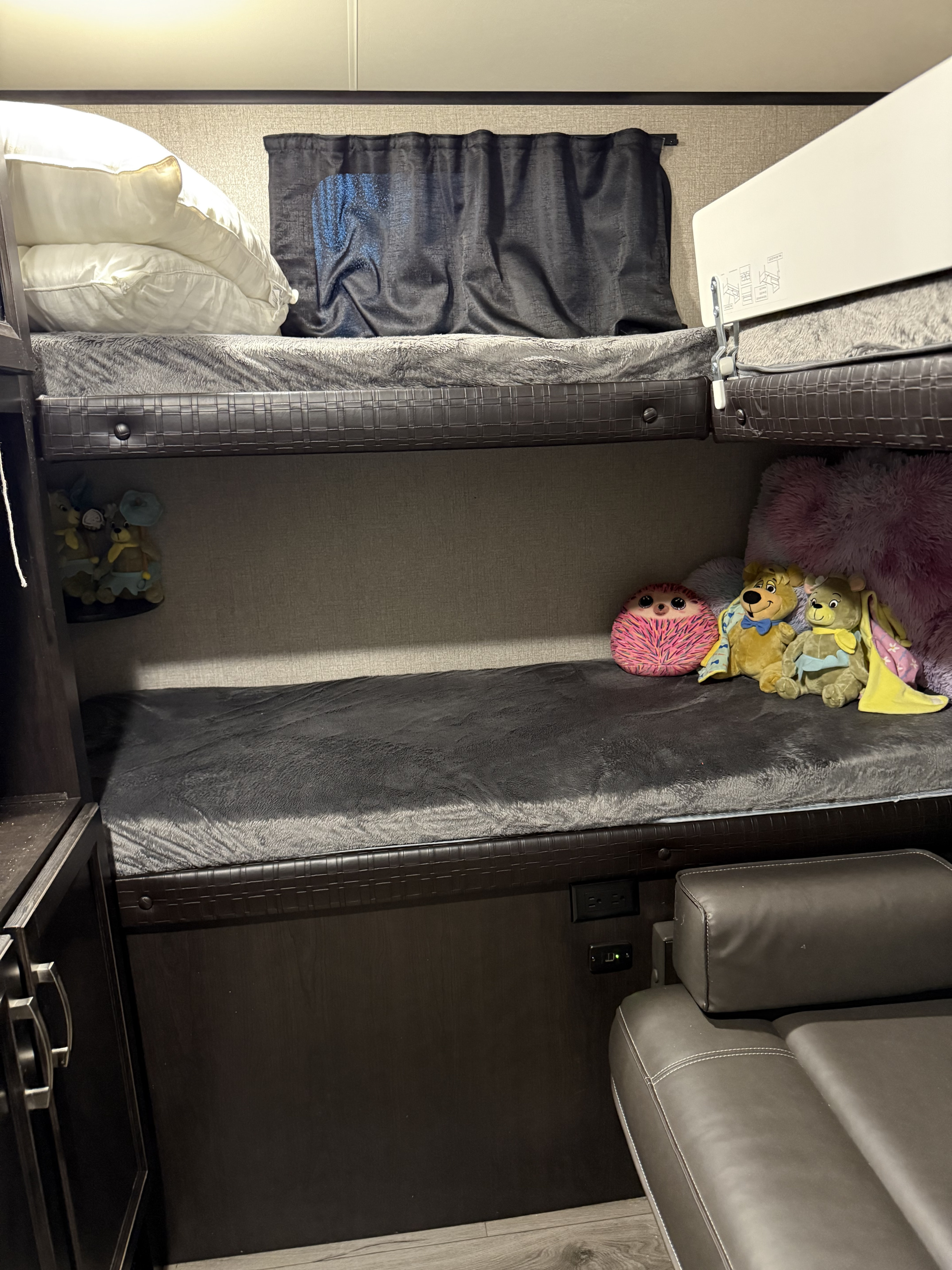 Cozy RV rental bunk beds with pillows, blankets, and stuffed animals, offering comfortable sleeping space.. Jayco Jay Feather 2021