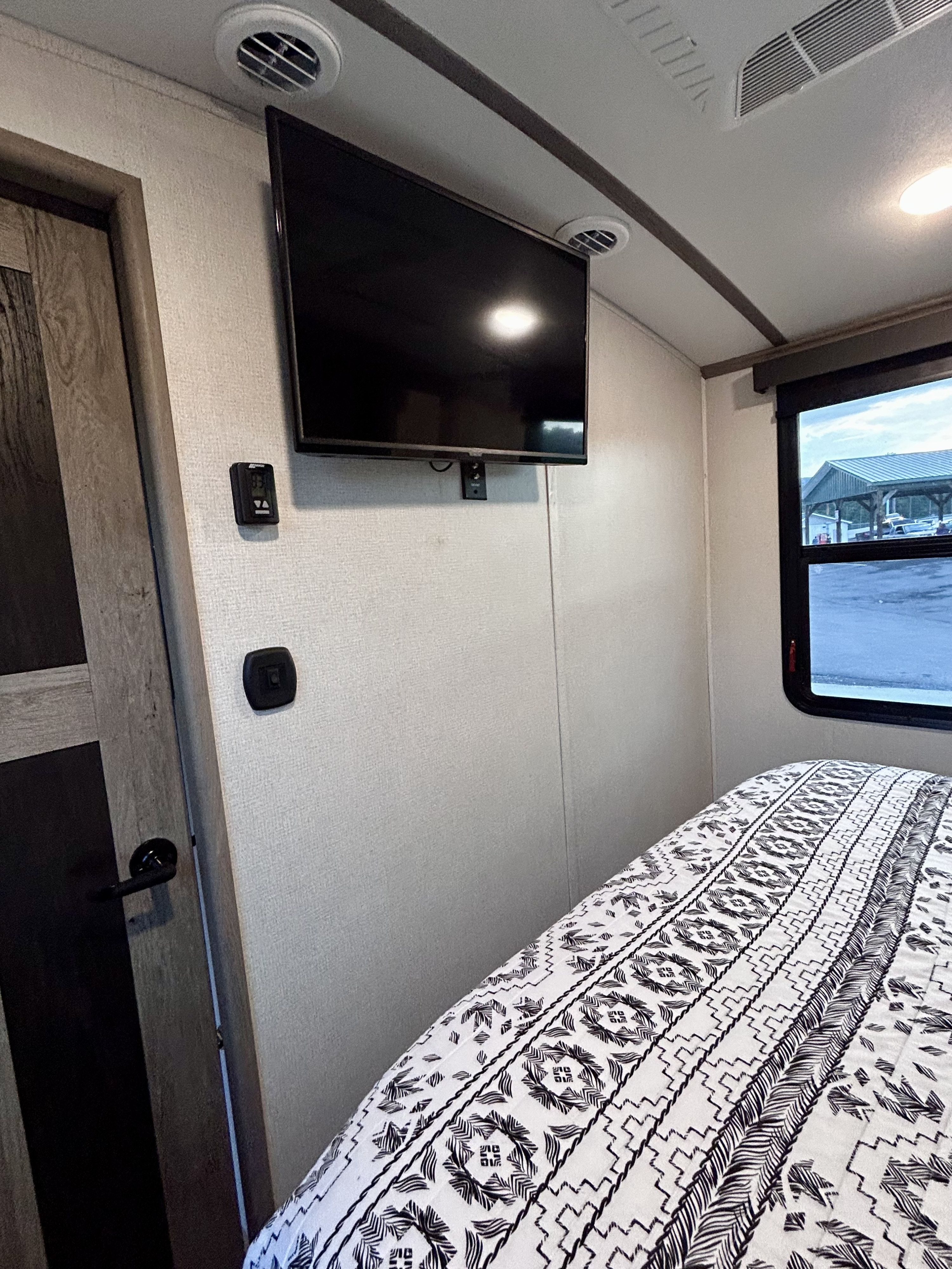 Cozy RV rental bedroom featuring a wall-mounted TV, comfy bed, and modern amenities for your travel adventures.. Keystone RV Outback 2021