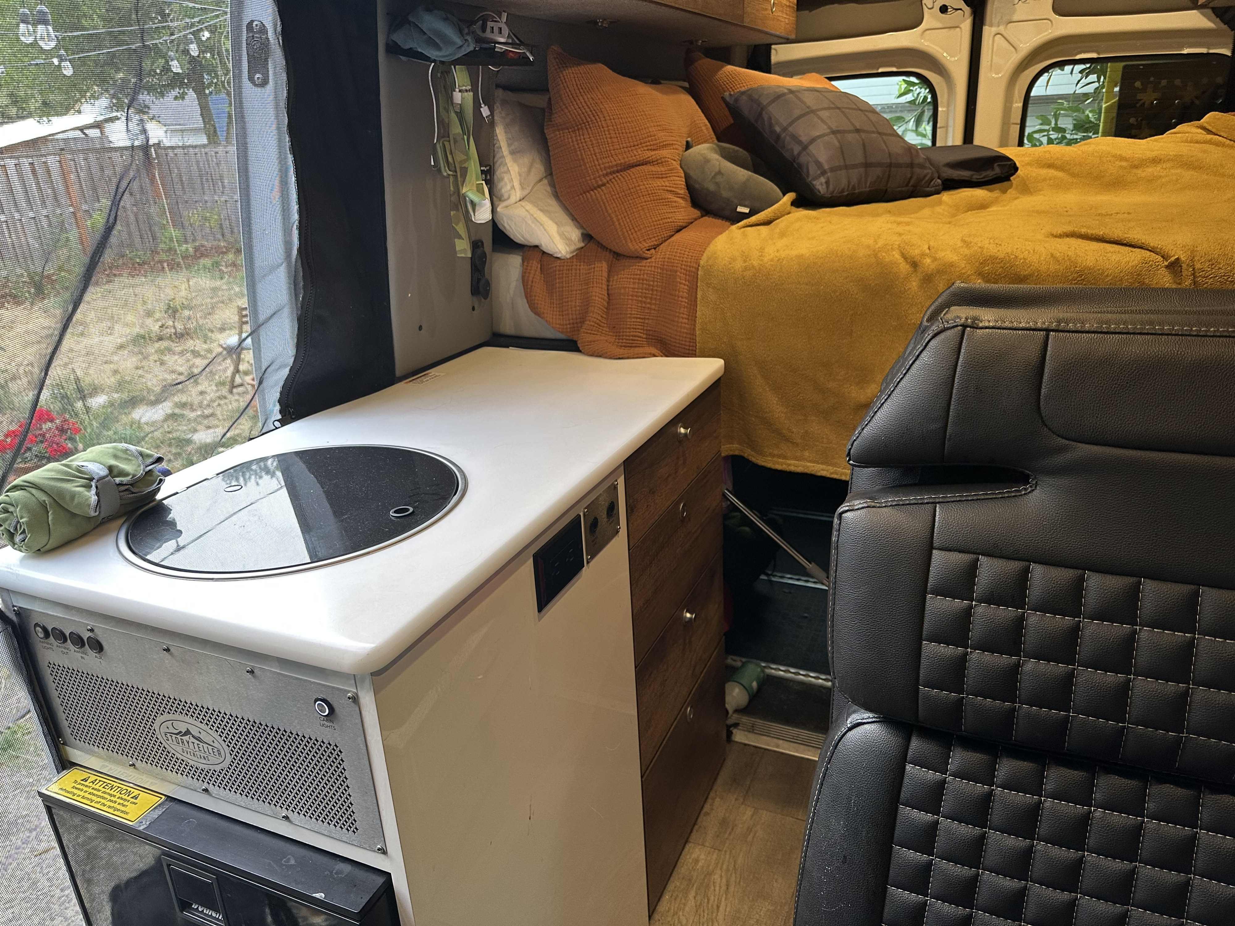 Spacious RV rental interior featuring a compact kitchen, cozy bed, and scenic views for comfortable road trips.. Storyteller Overland Storyteller Overland Class B 2021