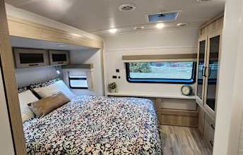 Inside an RV rental bedroom: a comfy queen bed, overhead storage, window, desk, and wardrobe. Perfect for your travels.. Forest River Flagstaff Super Lite 2024