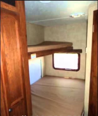 RV rental bunk beds. Inside a compact RV interior, a sleeping area features two bunks (one floor-level) and a window.. R-Vision Super Sport 2010